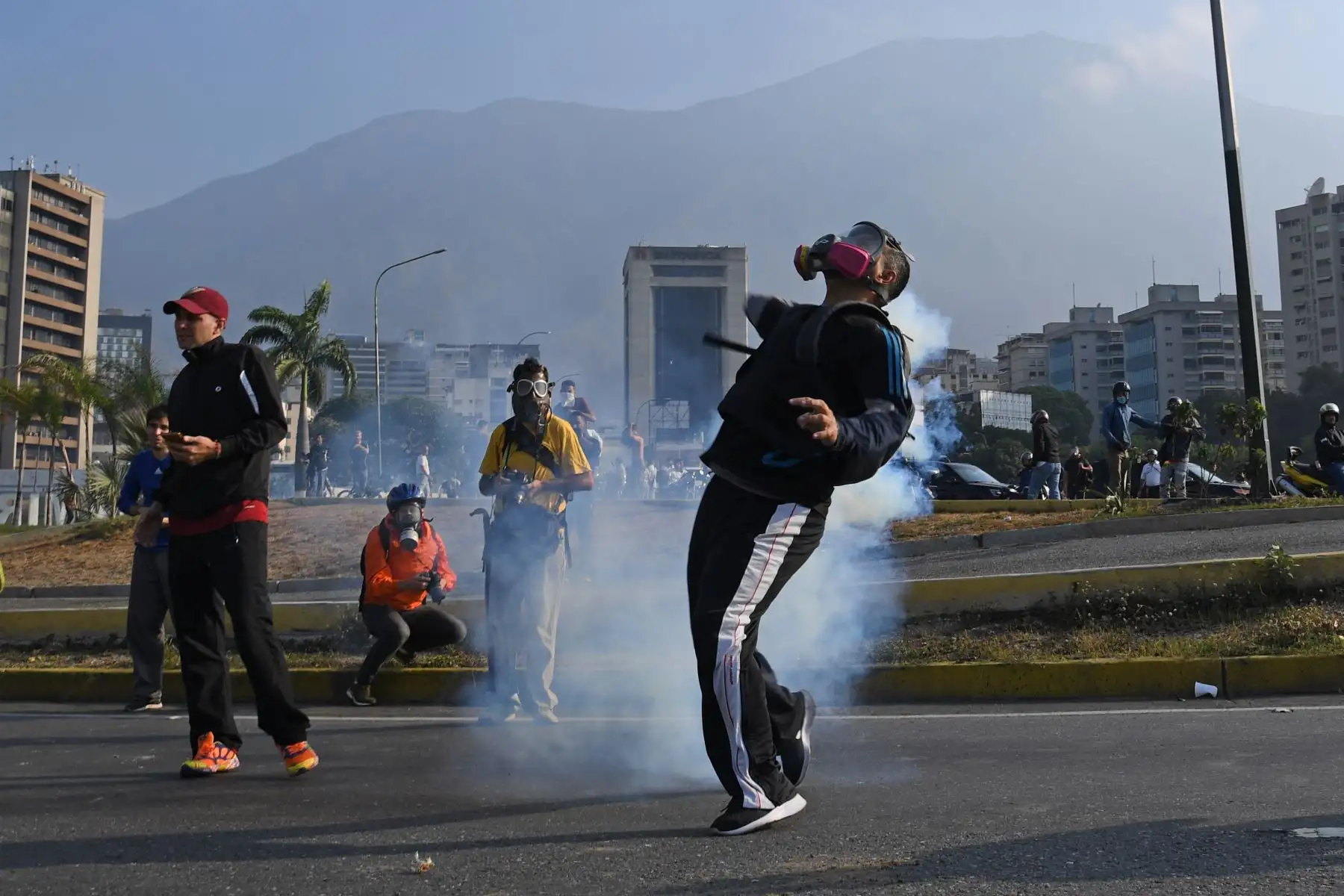 Simpatizantes del presidente interno Juan Guaidó se protegen de las bombas lacrimógenas que las fuerzas de seguridad leales al Gobierno de Nicolás Maduro lanzan en la base militar de La Carlota, donde se encuentra el presidente interino Juan Guaidó y un grupo de militares que le apoyan.Foto: AFP Simpatizantes del presidente interno Juan Guaidó se protegen de las bombas lacrimógenas que las fuerzas de seguridad leales al Gobierno de Nicolás Maduro lanzan en la base militar de La Carlota, donde se encuentra el presidente interino Juan Guaidó y un grupo de militares que le apoyan.Foto: AFP