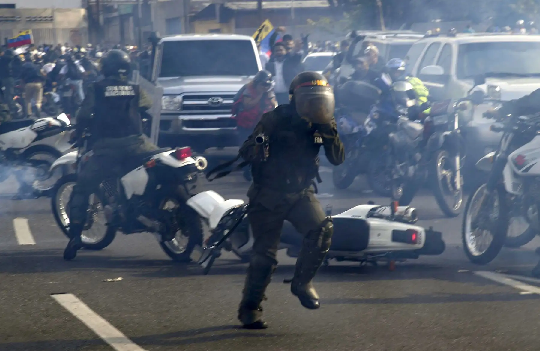 Miembros de la Guardia Nacional Bolivariana leales a Nicolás Maduro corren bajo una nube de gas lacrimógeno luego de ser rechazados por guardias que apoyan al presidente interino Juan Guaido, frente a la base militar de La Carlota en Caracas. Foto: AFP