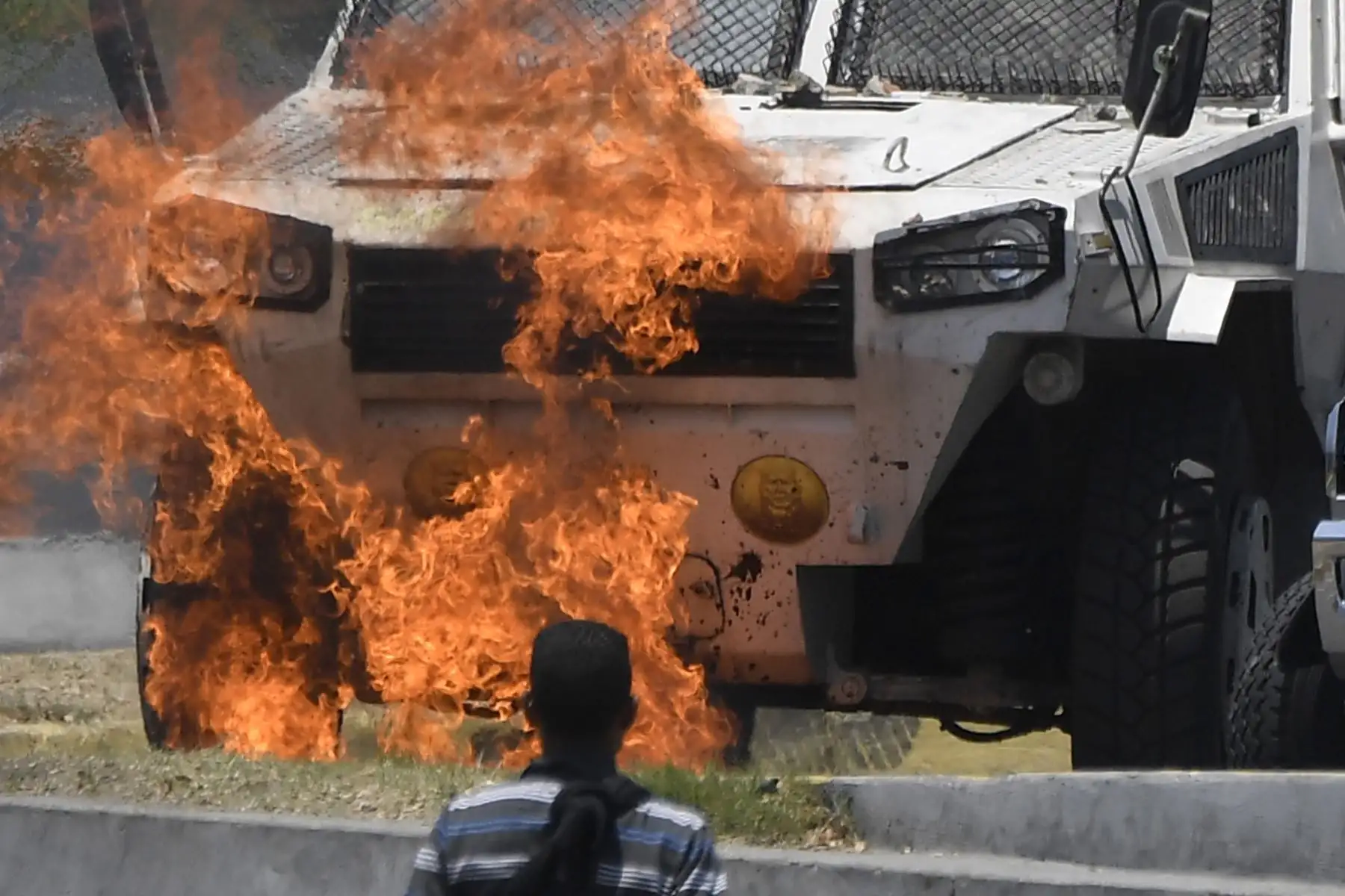 Manifestantes caminan cerca de un autobús en llamas durante los enfrentamientos con soldados leales a Nicolás Maduro. Foto: AFP