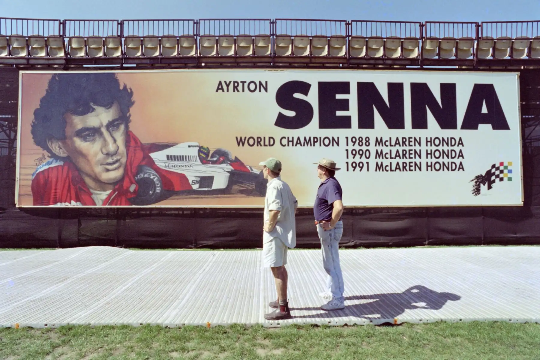 Trabajadores de una construcción miran hacia arriba en un mural gigante de Ayrton Senna en la parte trasera de una tribuna en Albert Park, sede del Gran Premio de F1 de Australia  en Melbourne el 5 de marzo de 1996. 
Foto: AFP