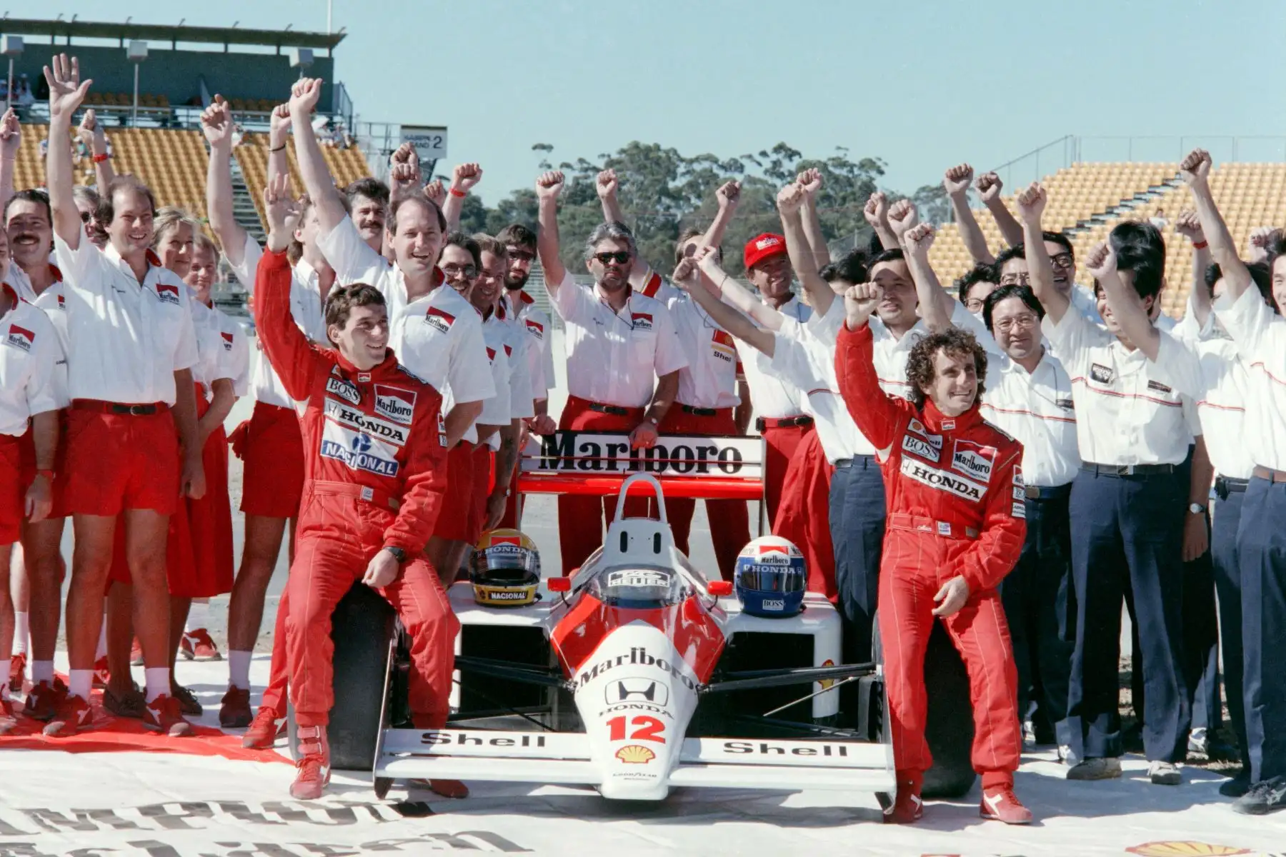Sentado en su McLaren Honda, el nuevo campeón mundial Ayrton Senna (L) de Brasil levanta su puño junto con su compañero de equipo Alain Prost de Francia y todos los miembros del equipo McLaren Honda, antes de la clasificación final para el Gran Premio de F1 de Australia en Adelaide en noviembre. 12, 1988. 
Foto:AFP