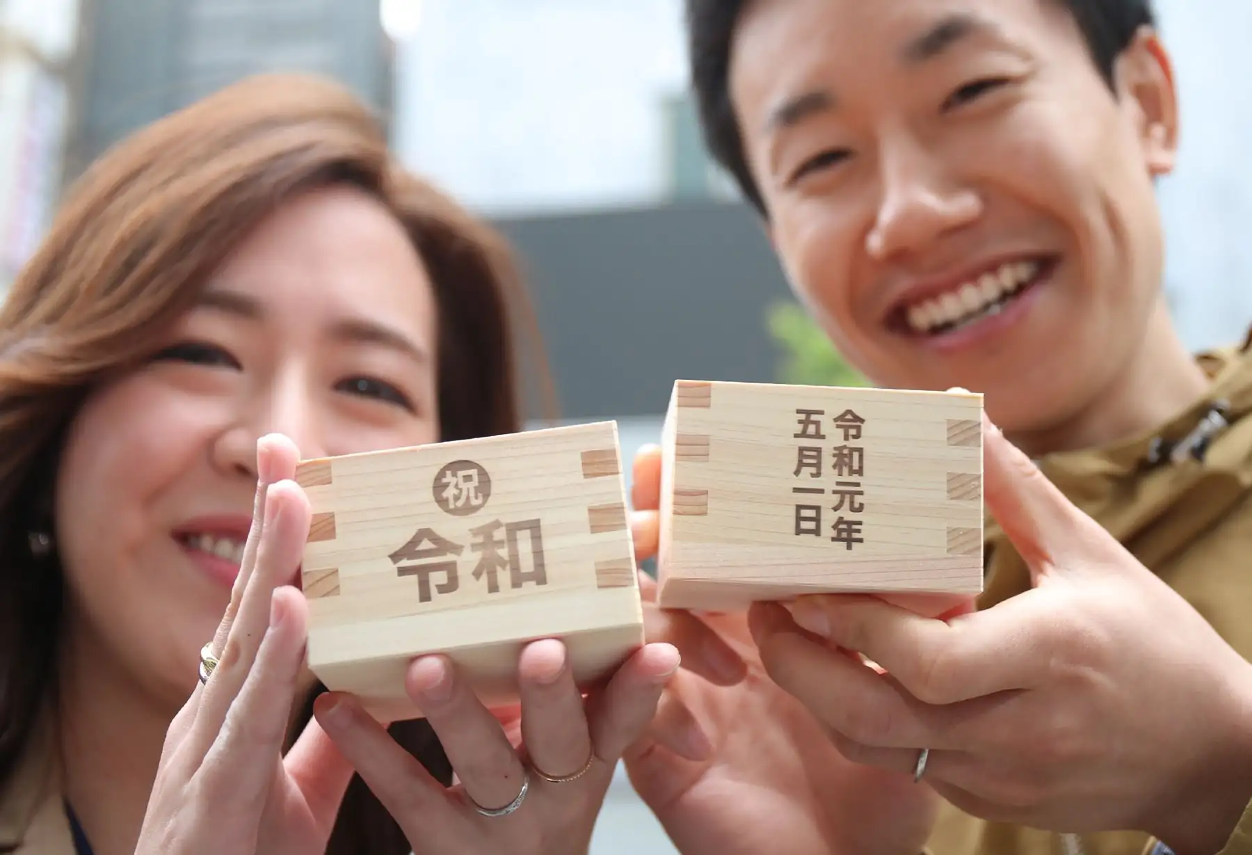 Una pareja sostiene sus cajas de sake que indican "Reiwa"  con el significado 