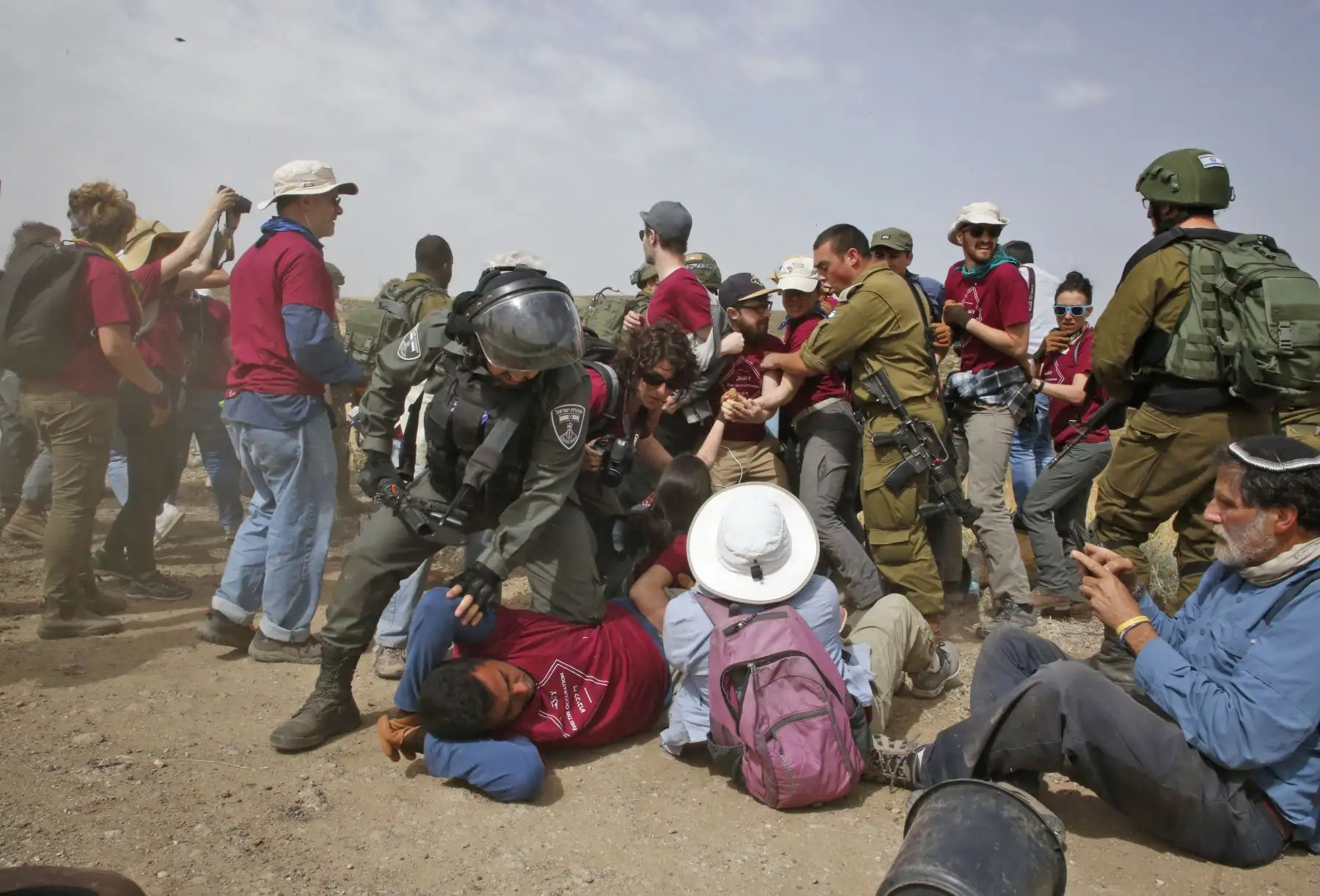Fuerzas israelíes inmovilizan a activistas mientras que militantes extranjeros, israelíes y palestinos intentan despejar un camino que conduce a las aldeas palestinas, cerca de la ciudad de Yatta en la Cisjordania. Foto: AFP