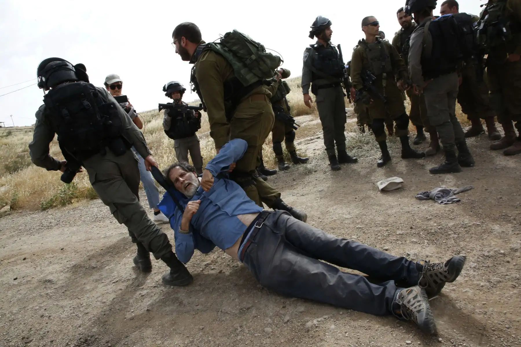 Fuerzas israelíes inmovilizan a activistas mientras que militantes extranjeros, israelíes y palestinos intentan despejar un camino que conduce a las aldeas palestinas, cerca de la ciudad de Yatta en la Cisjordania. Foto: AFP