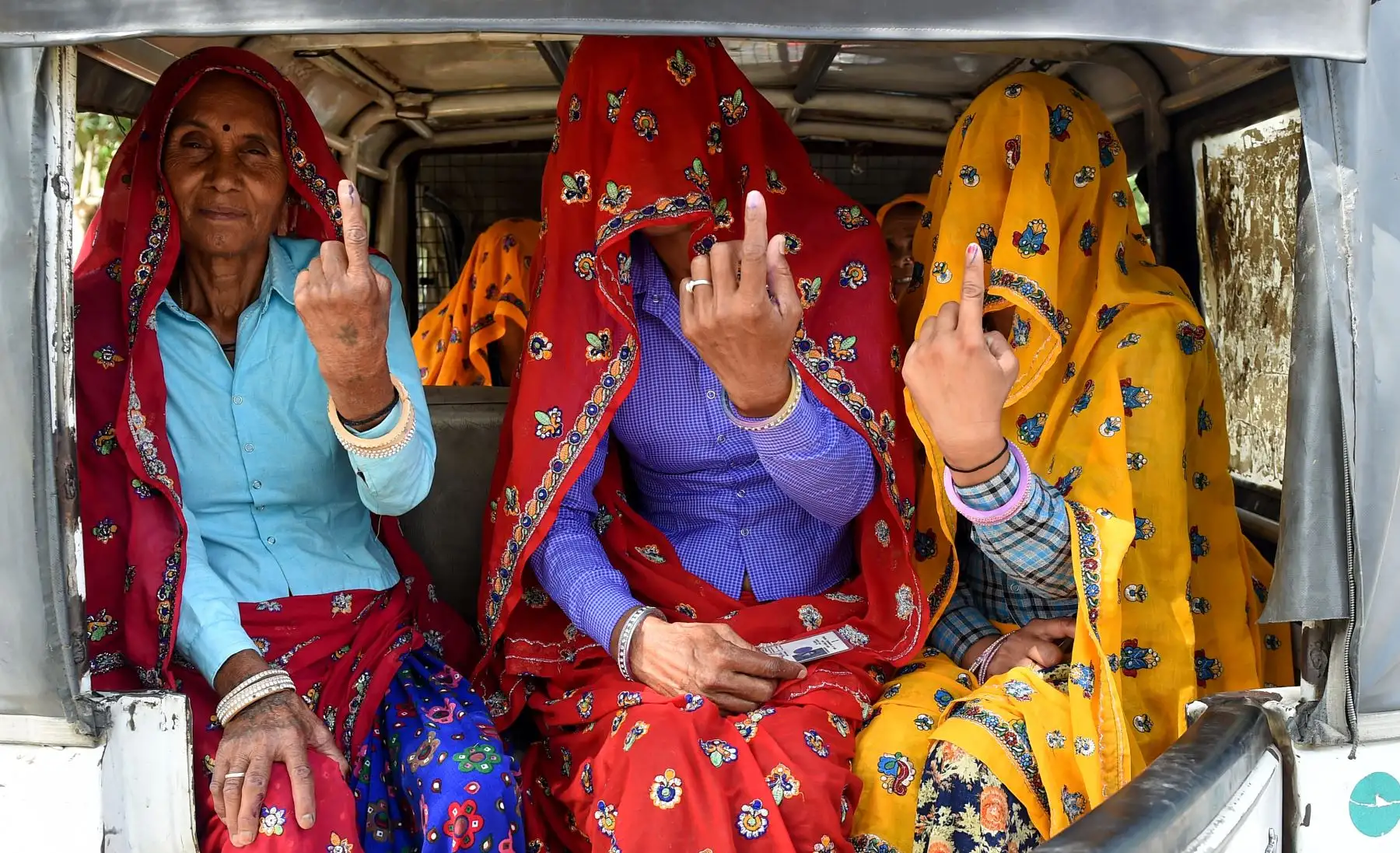 Mujeres de la india se sientan dentro de un auto-rickshaw mientras muestran su dedo marcado con tinta después de emitir su voto: Foto: AFP