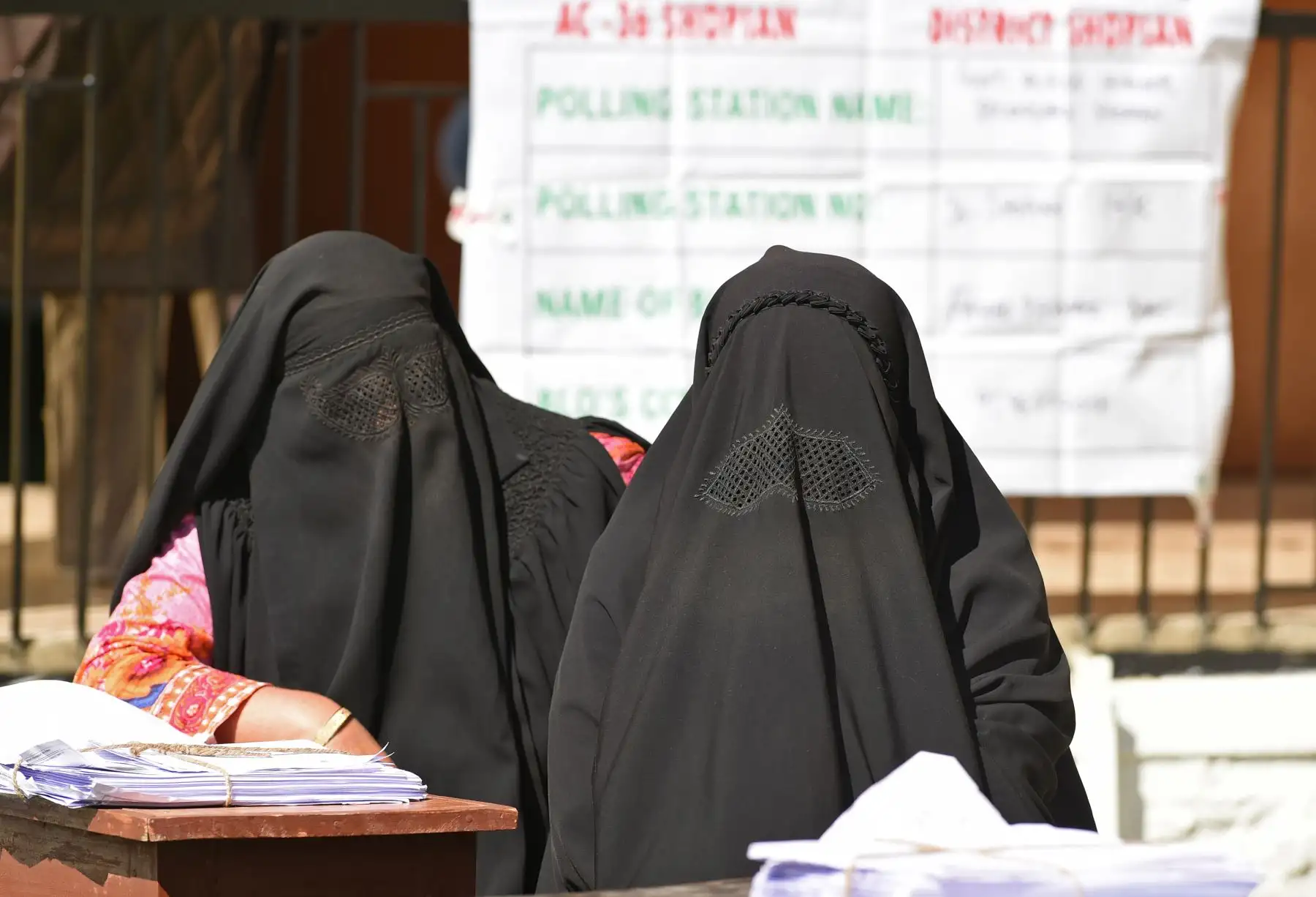 Las mujeres vestidas con burka que trabajan como agentes electorales se sientan en un centro de votación. Foto: AFP