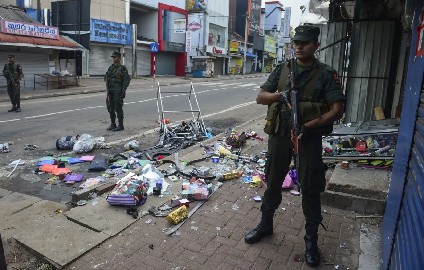 Policías de Sri Lanka hacen guardia frente a una tienda dañada después de un atentado en Sri Lanka. Foto: AFP