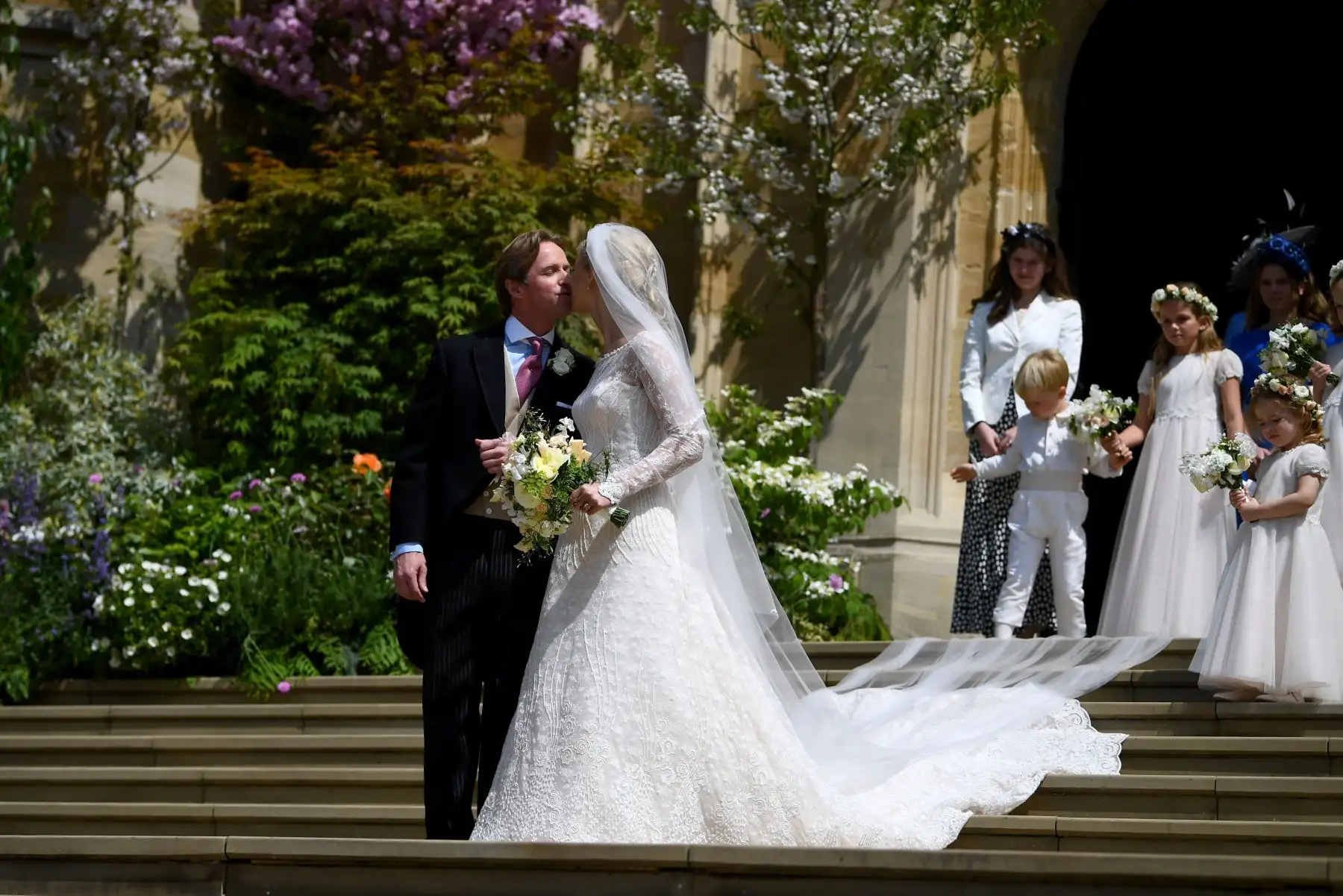 Los recién casados Thomas Kingston (L) y Lady Gabriella Windsor se besan en los escalones con sus damas de honor, los muchachos de la página y los invitados después de su ceremonia de boda, en la Capilla de San Jorge en el Castillo de Windsor, Windsor, al oeste de Londres.
Lady Gabriella es la hija del príncipe y la princesa Michael de Kent. El príncipe Michael, es el primo de la reina Isabel II.
Foto:AFP