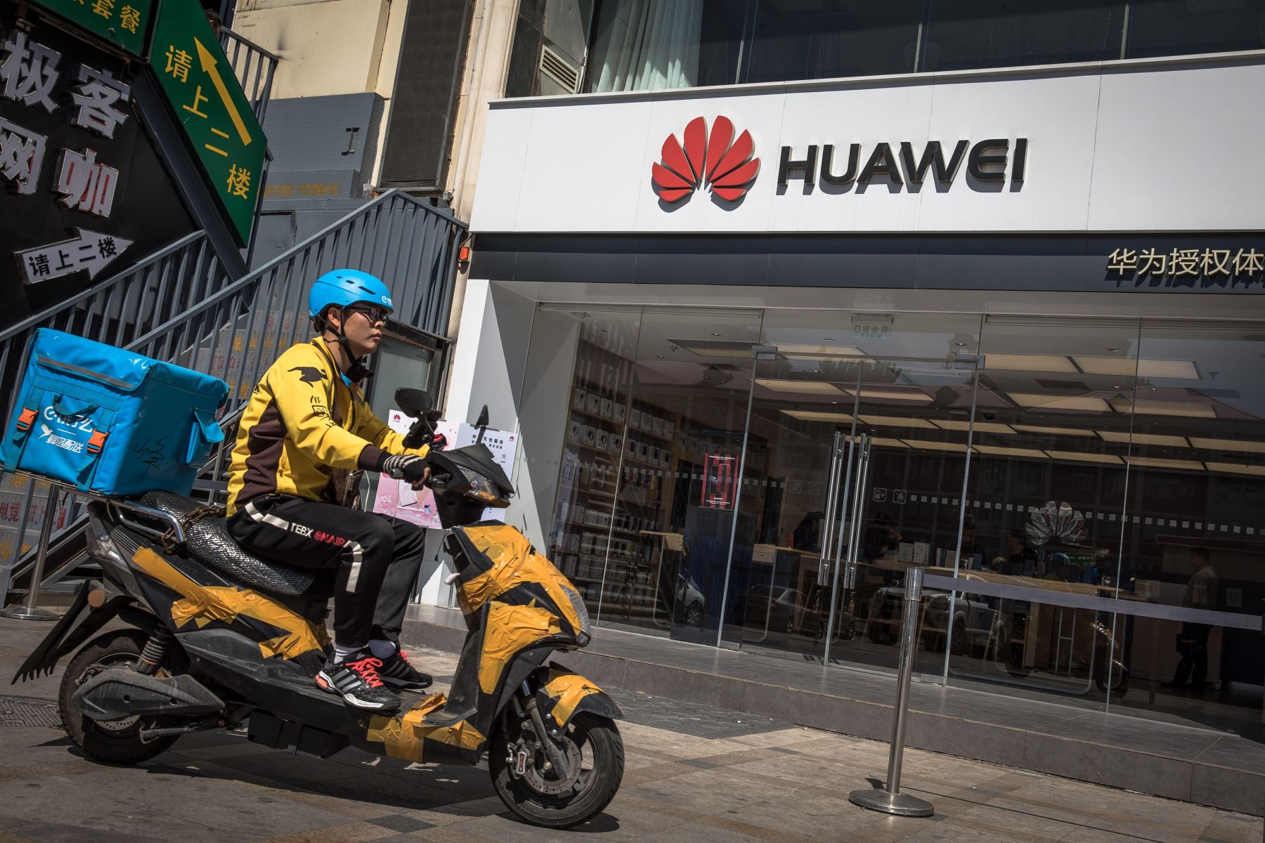 Un repartidor monta en motocicleta frente a una tienda de Huawei, este lunes en Pekín (China). El veto de Google y otras tecnológicas estadounidenses a Huawei podría frustrar la aspiración del fabricante chino de convertirse en breve en el mayor fabricante de móviles del mundo, donde aún está por detrás de Samsung pese a vender más de siete móviles por segundo. Foto: EFE