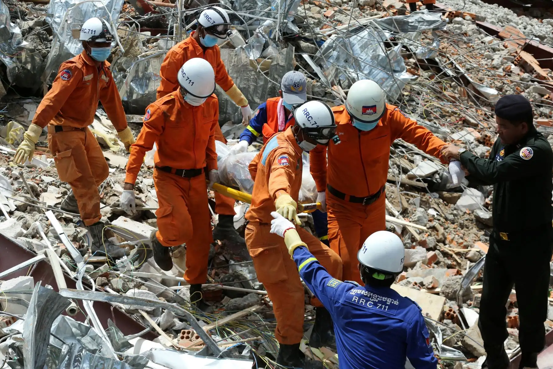 Los trabajadores de rescate llevan el cuerpo de una víctima que sacaron de los escombros un día después de que un edificio en construcción colapsara en Sihanoukville. Los trabajadores de rescate recogieron entre los escombros a 17 personas fallecidas de un edificio colapsado de propiedad china . 
Foto: AFP