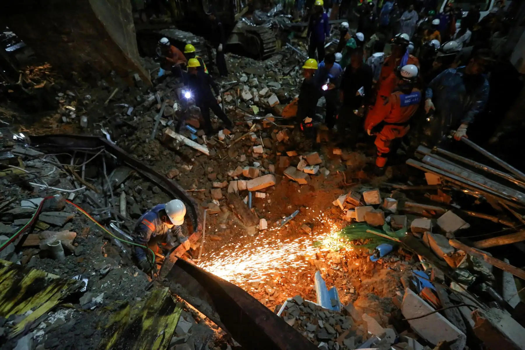 Los trabajadores de rescate llevan el cuerpo de una víctima que sacaron de los escombros un día después de que un edificio en construcción colapsara en Sihanoukville. Los trabajadores de rescate recogieron entre los escombros a 17 personas fallecidas de un edificio colapsado de propiedad china . 
Foto: AFP