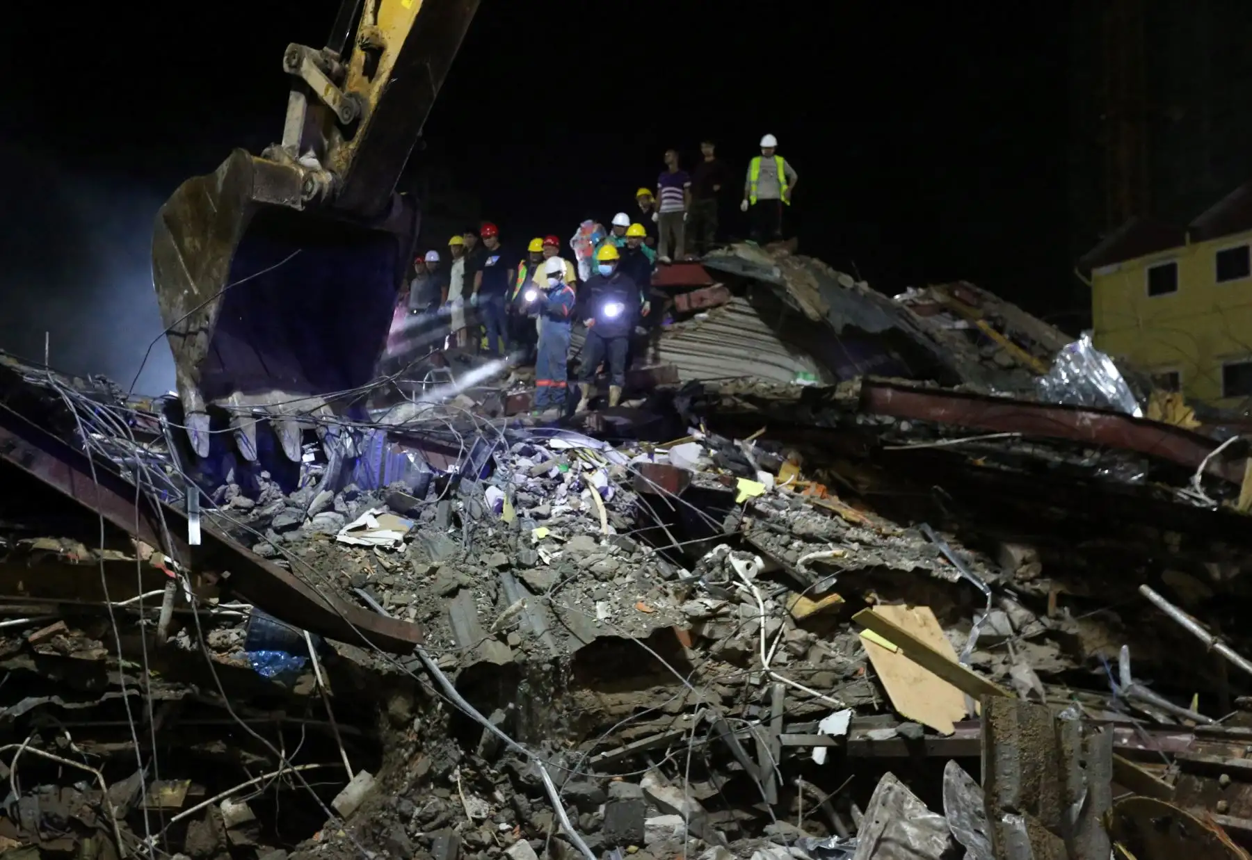 Los trabajadores de rescate llevan el cuerpo de una víctima que sacaron de los escombros un día después de que un edificio en construcción colapsara en Sihanoukville. Los trabajadores de rescate recogieron entre los escombros a 17 personas fallecidas de un edificio colapsado de propiedad china . 
Foto: AFP