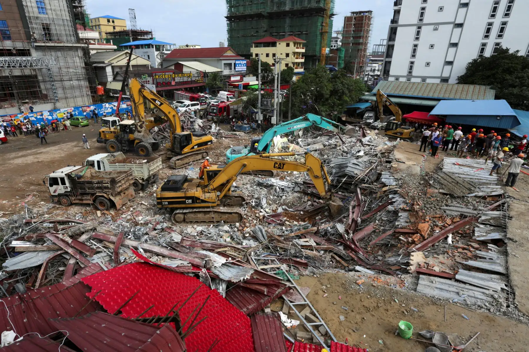 Los trabajadores de rescate llevan el cuerpo de una víctima que sacaron de los escombros un día después de que un edificio en construcción colapsara en Sihanoukville. Los trabajadores de rescate recogieron entre los escombros a 17 personas fallecidas de un edificio colapsado de propiedad china . 
Foto: AFP