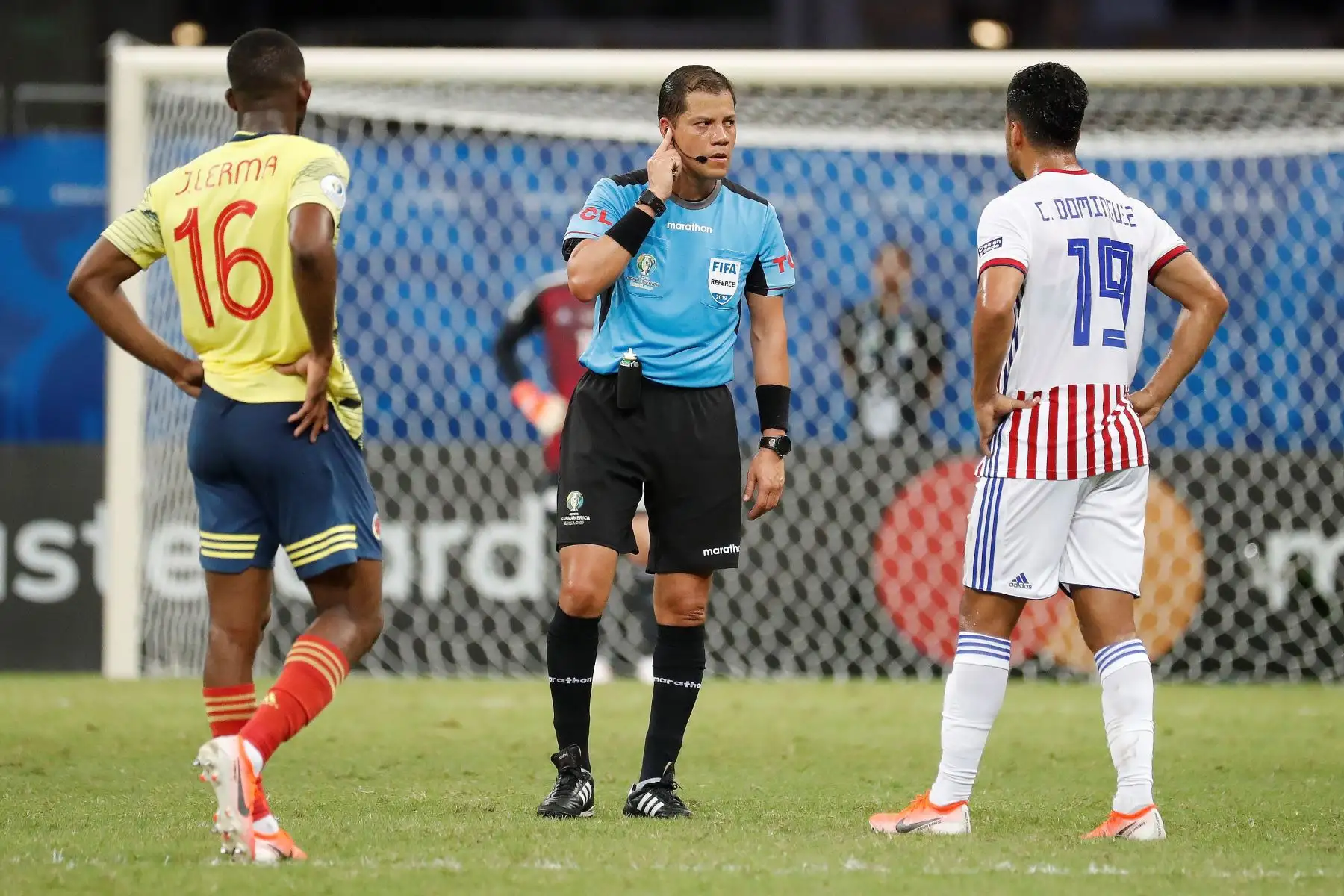 El árbitro Victor Hugo Carrillo (c) recibe instrucciones del centro VAR, durante el partido Colombia-Paraguay del Grupo B de la Copa América de Fútbol 2019.
Foto: AFP