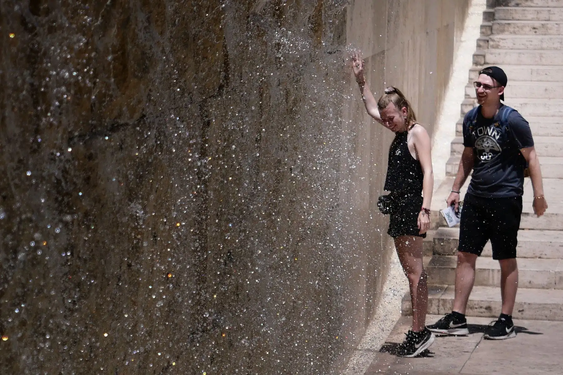 La gente se refresca en una fuente de cascada durante una ola de calor en Roma. Foto: AFP