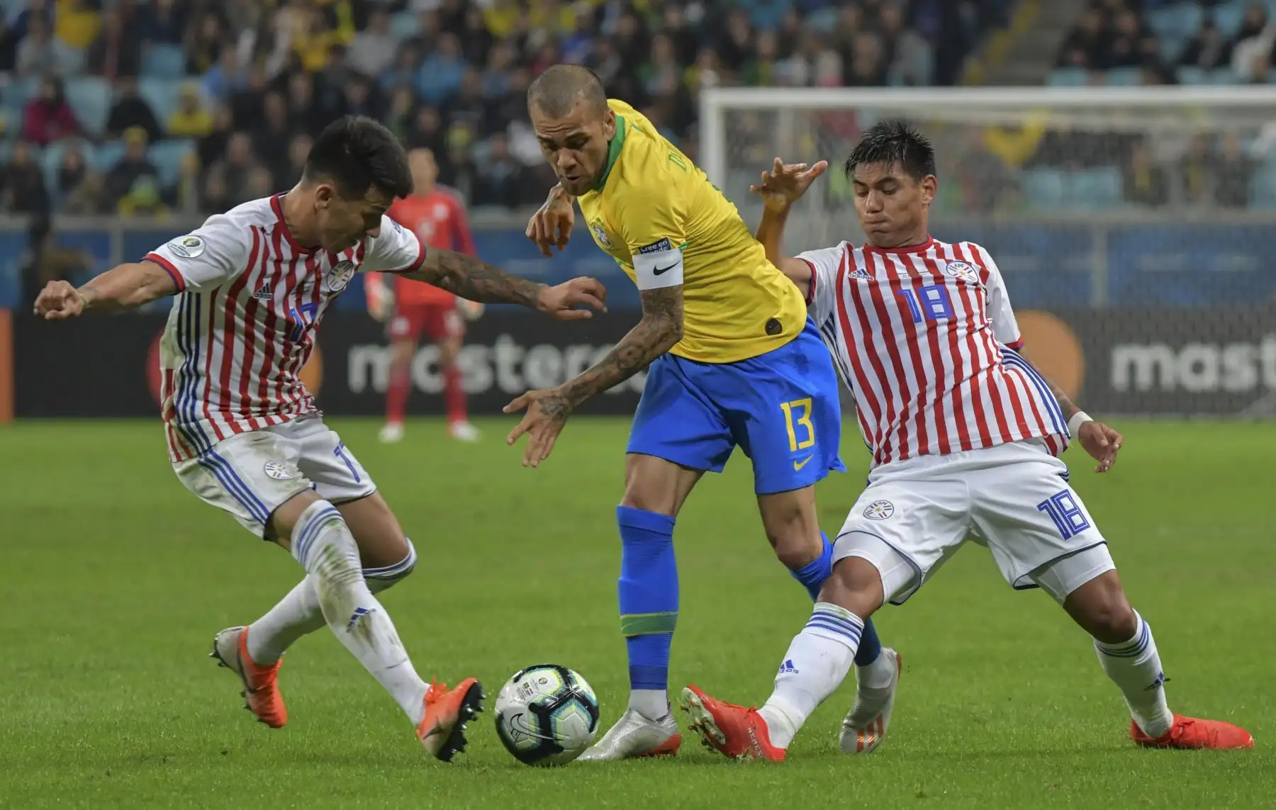 Dani Alves (C) de razil está marcado por Hernán Pérez (L) de Paraguay y Santiago Arzamendia durante su partido de cuartos de final del torneo de fútbol de la Copa América en el Gremio Arena de Porto Alegre, Brasil.Foto:AFP