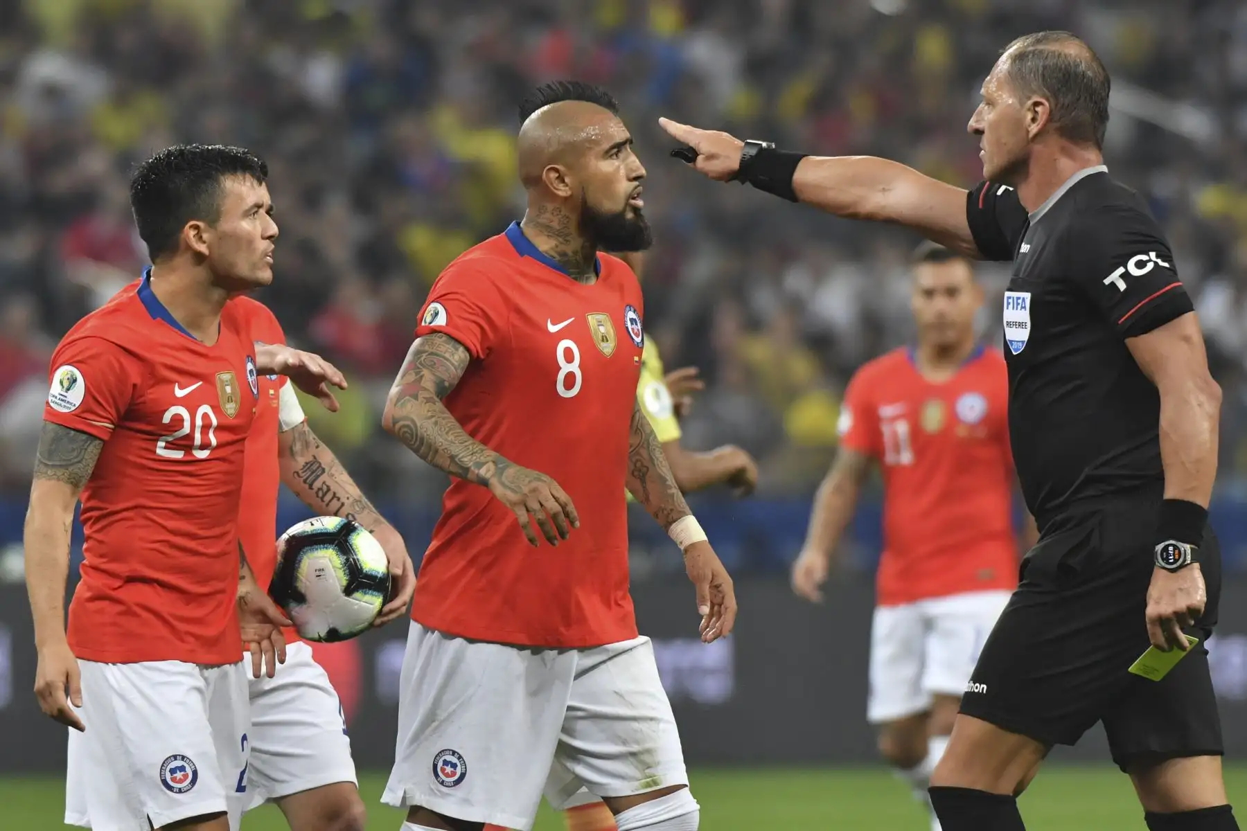 El árbitro argentino Néstor Pitana le otorga una tarjeta amarilla al jugador de Chile Charles Aranguiz (L) mientras conduce el partido de cuartos de final del torneo de fútbol de la Copa América entre Colombia y Chile en el Corinthians Arena de Sao Paulo, Brasil.Foto:AFP