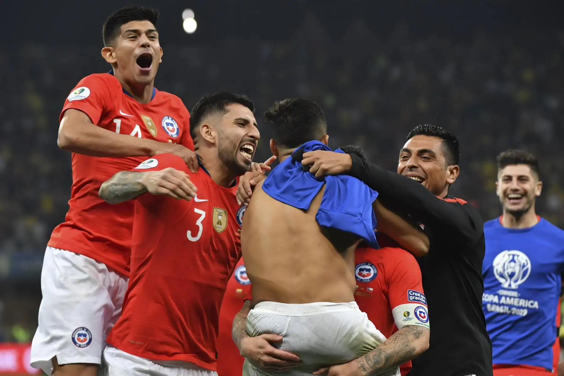 El chileno Alexis Sánchez (sin camiseta) celebra con sus compañeros de equipo luego de marcar su penalización para derrotar a Colombia en el tiroteo después de empatar 0-0 durante su partido de cuartos de final del torneo de fútbol de la Copa América en el Corinthians Arena en Sao Paulo, Brasil.Foto.AFP