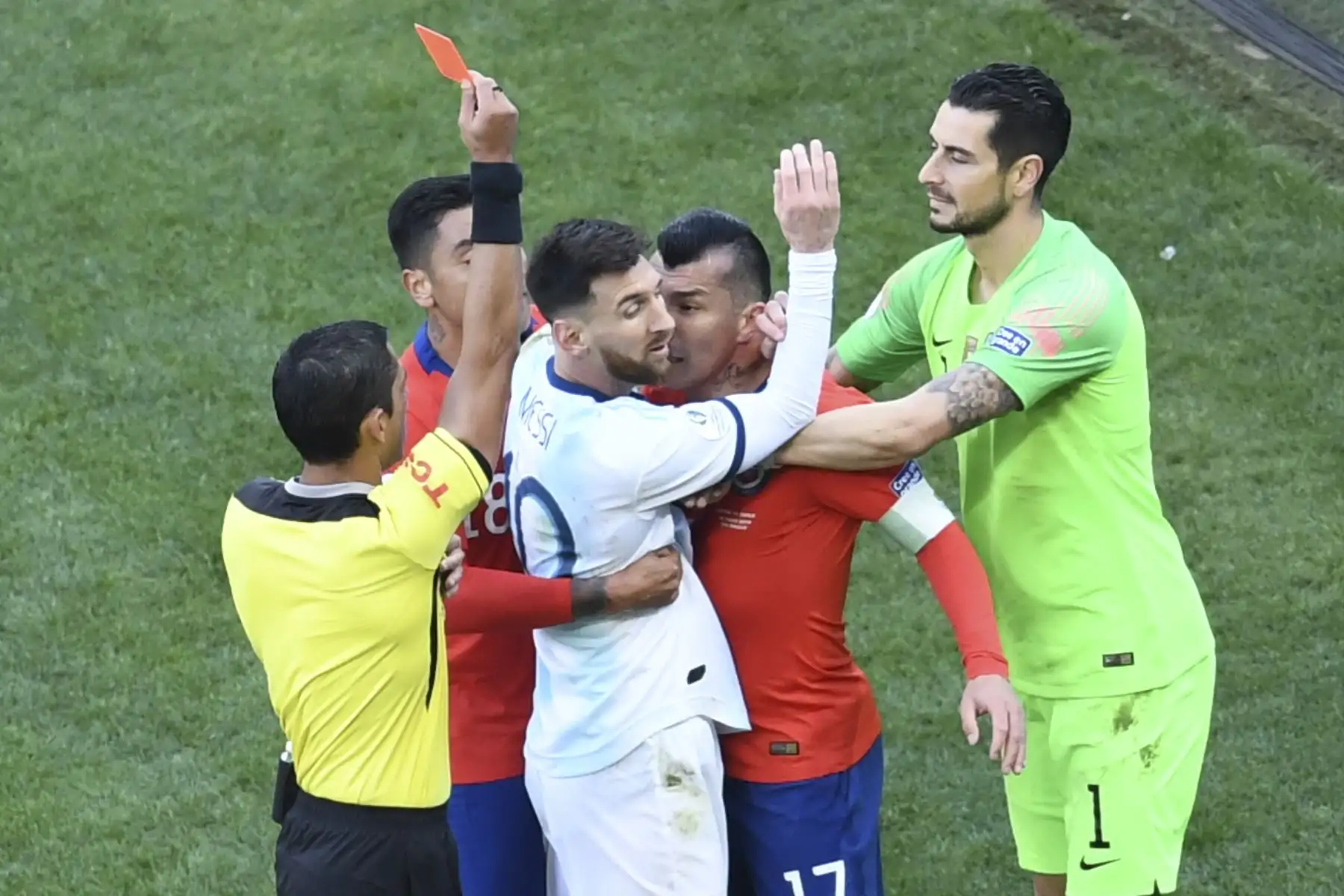 El árbitro paraguayo Mario Díaz de Vivar muestra la tarjeta roja al argentino Lionel Messi y al chileno Gary Medel durante el partido por el tercer lugar en el torneo de fútbol de la Copa América en el Corinthians Arena en Sao Paulo, Brasil.Foto: AFP