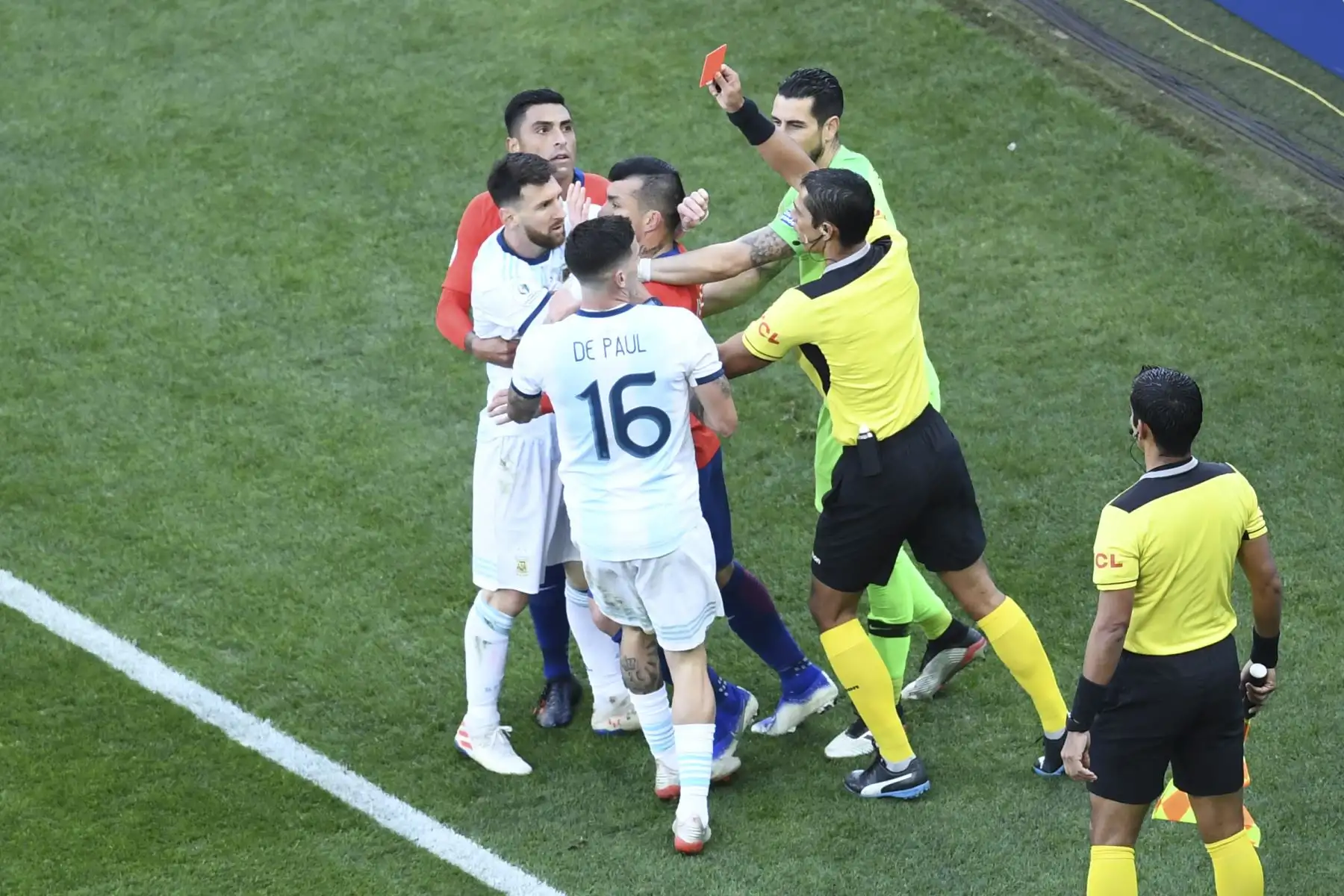 El árbitro paraguayo Mario Díaz de Vivar muestra la tarjeta roja al argentino Lionel Messi y al chileno Gary Medel durante el partido por el tercer lugar en el torneo de fútbol de la Copa América.
Foto: AFP