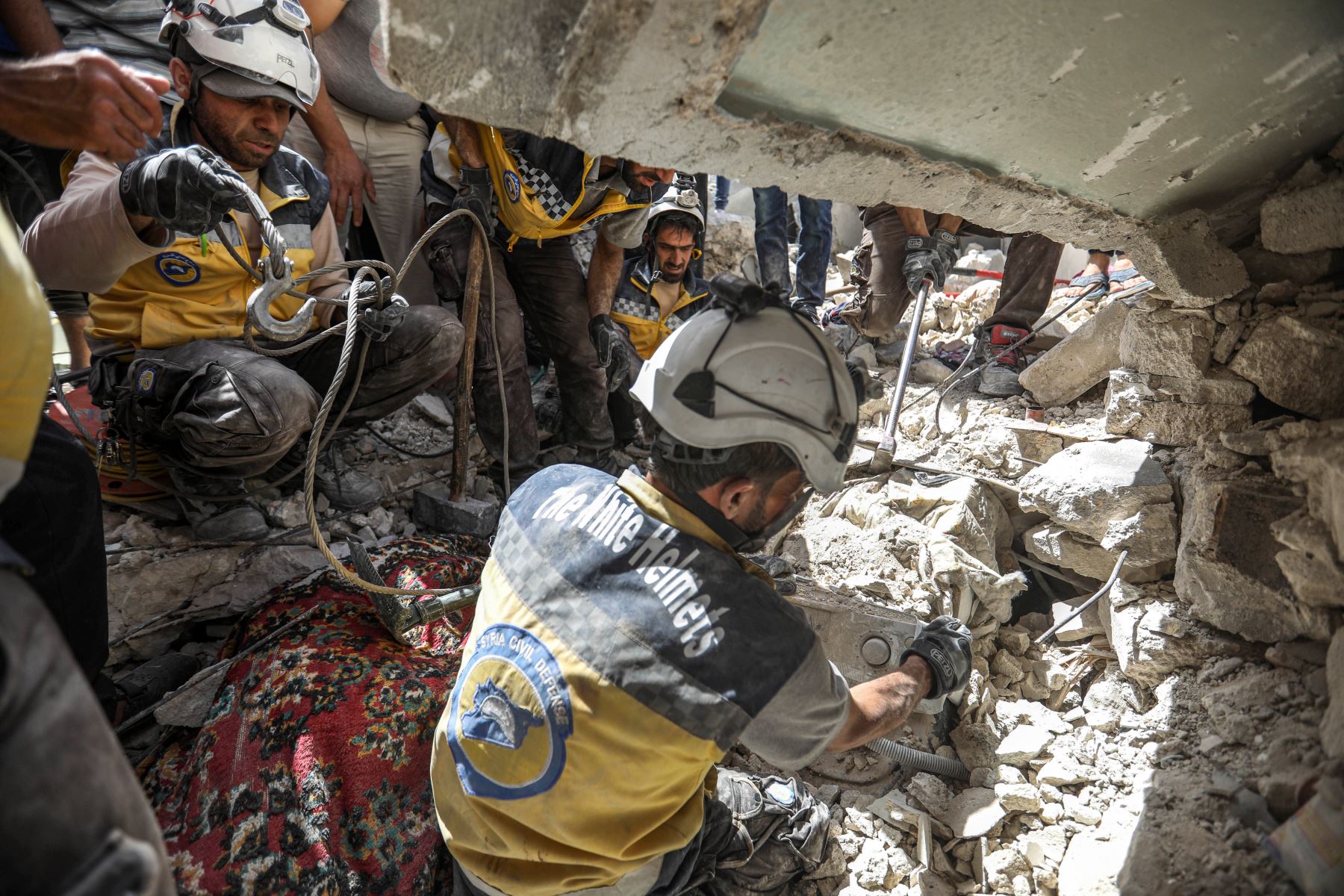 Miembros de la Defensa Civil Siria encuentran víctimas tras un ataque aéreo en la ciudad de Ariha, en el  Siria. Foto: AFP