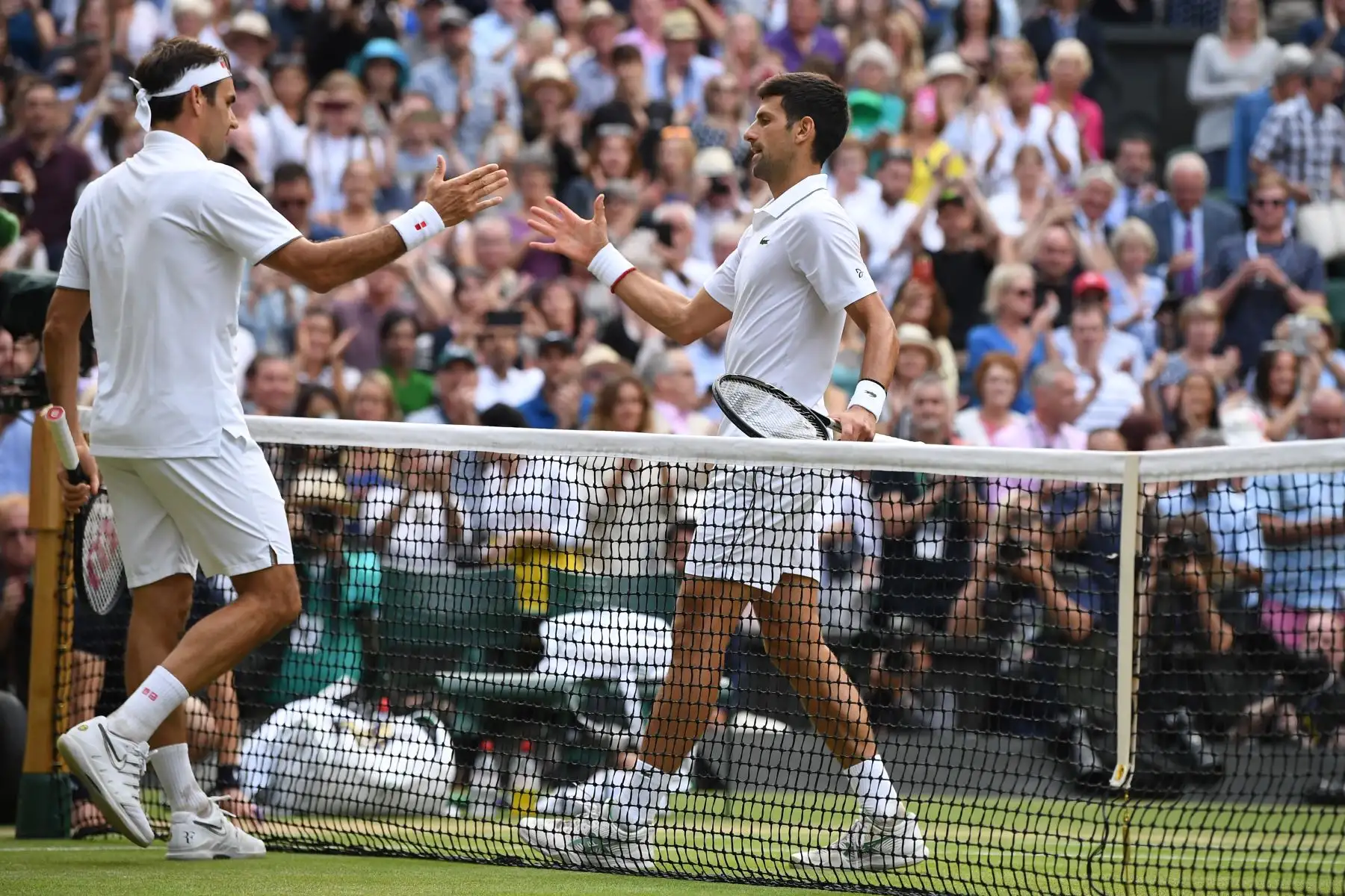 Novak Djokovic de Serbia le da la mano al Roger Federer de Suiza después de que Djokovic ganó la final de singles masculinos el día trece del Campeonato de Wimbledon 2019.
Foto. AFP