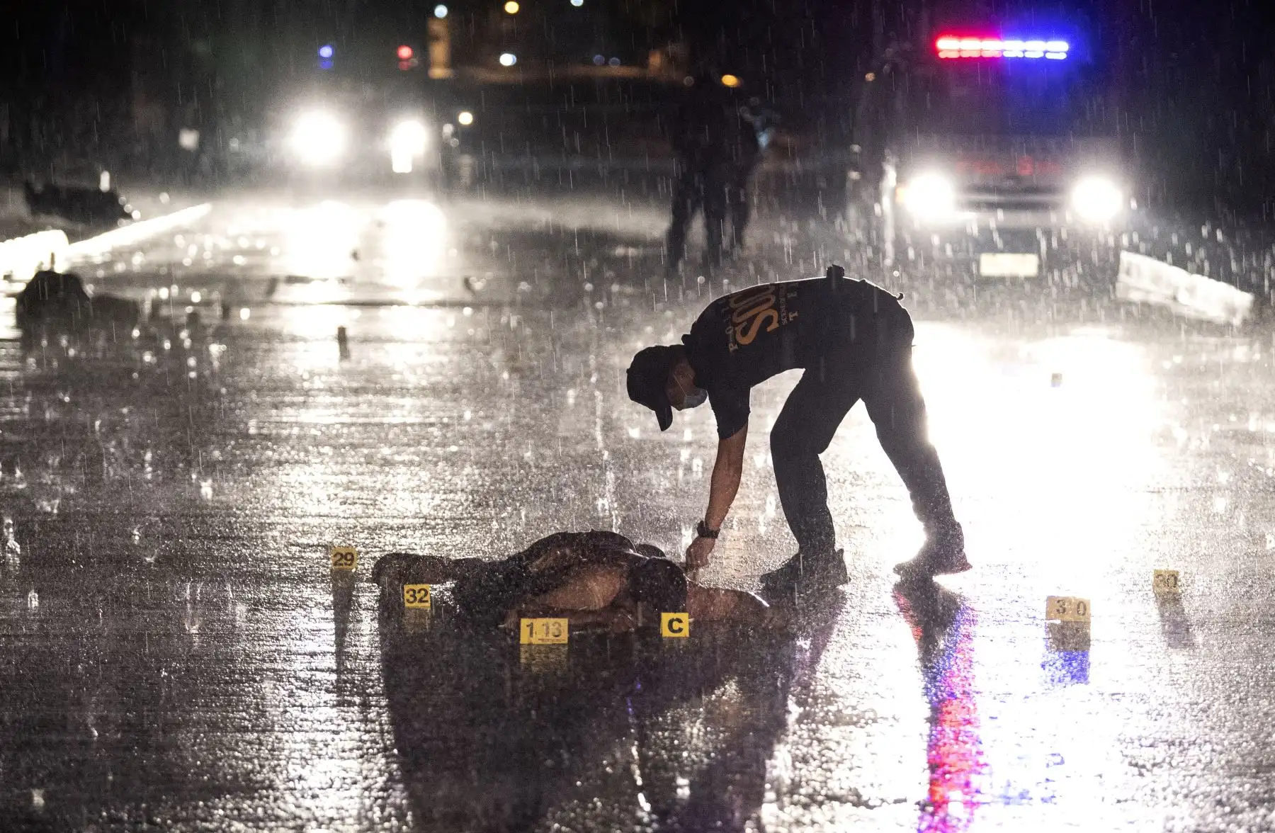Los oficiales de policía investigan una escena de un tiroteo mientras el cuerpo de un sospechoso yace en una calle en Manila. Tres sospechosos murieron a tiros luego de un intercambio de disparos durante una operación policial, con tres armas de fuego y un saquito de metanfetamina recuperado en la escena. AFP