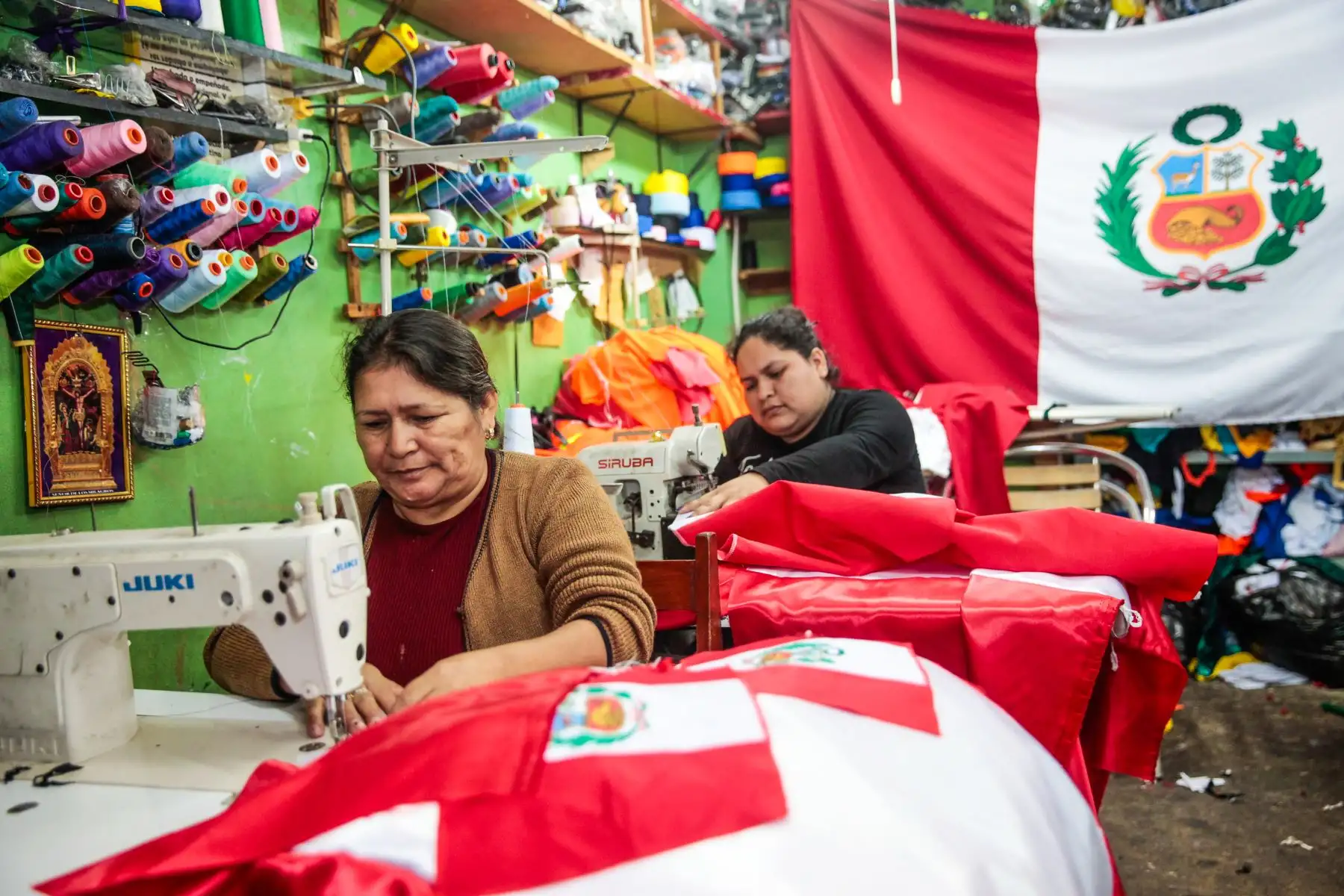 Toribia Rojas, pequeña empresaria, confecciona banderas en su taller del emporio textil de Gamarra. Elaboración y venta de banderas por fiestas patrias. 
Foto: ANDINA/Miguel Mejía Castro