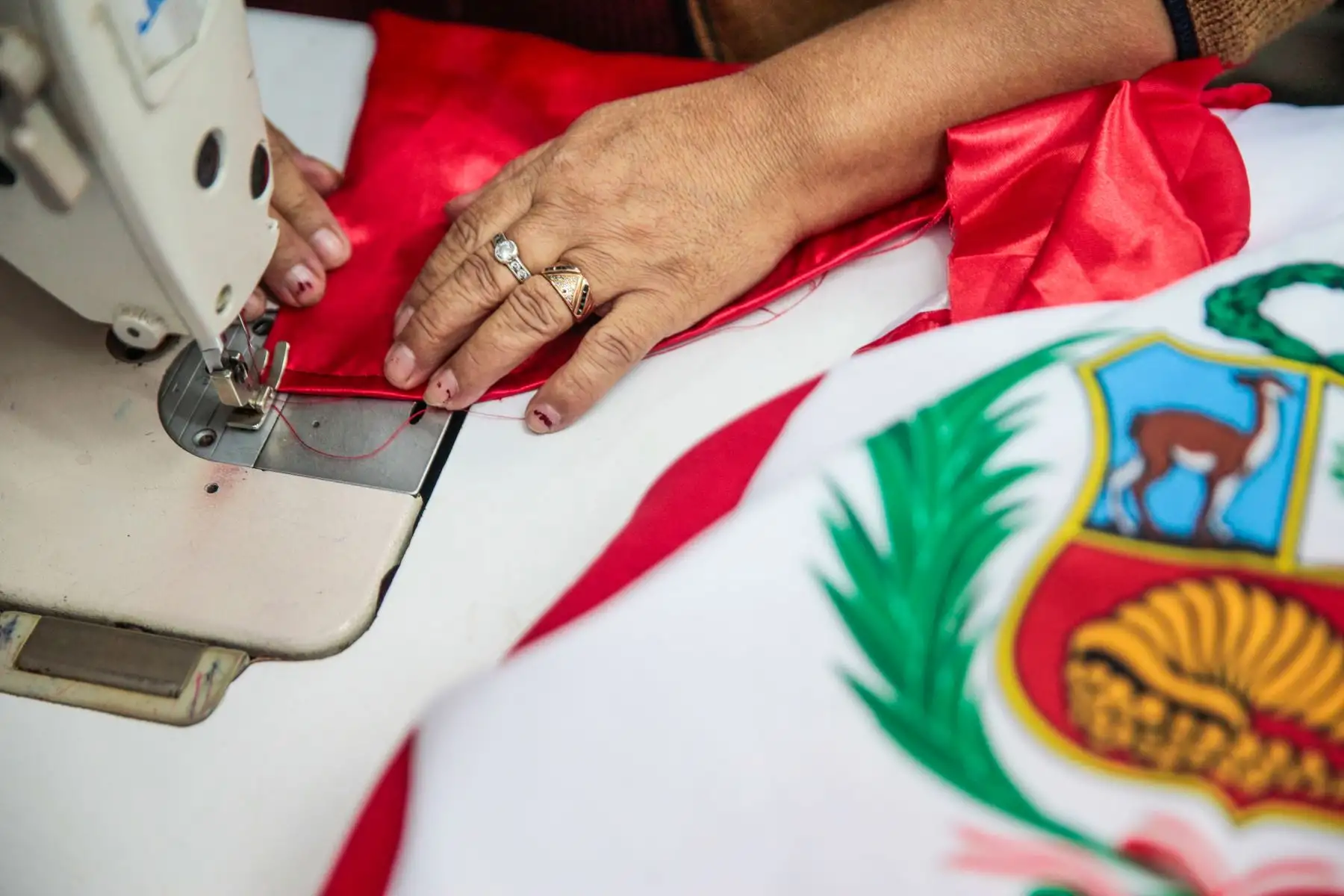 En el taller Keyla Sport, ubicado en el emporio textil de Gamarra, Toribia Rojas, confecciona banderas por fiestas patrias. 
Foto: ANDINA/Miguel Mejía Castro