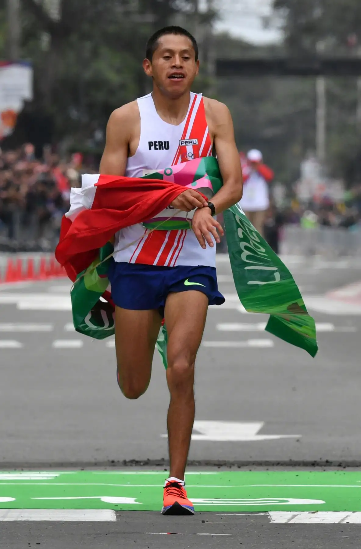 Christian Pacheco, de Perú, saluda a la gente cuando se acerca a la línea de meta para ganar la medalla de oro en la Maratón masculina de los Juegos Panamericanos Lima 2019 en Lima, Perú, el 27 de julio de 2019. Los Juegos Panamericanos duran hasta el 11 de agosto. AFP