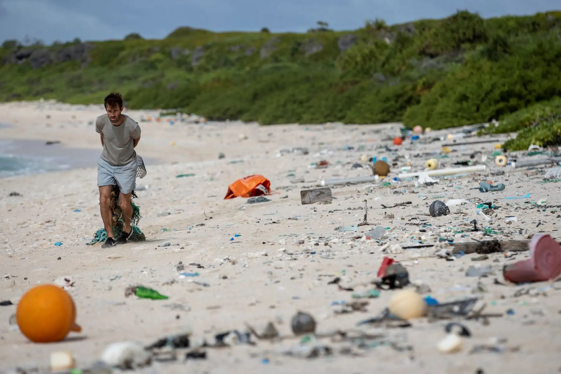 esta Imagen muestra a un miembro del equipo de limpieza de playas recogiendo basura de una playa en la isla Henderson, un miembro deshabitado del archipiélago de las Islas Pitcairn en el sur Océano Pacífico.AFP