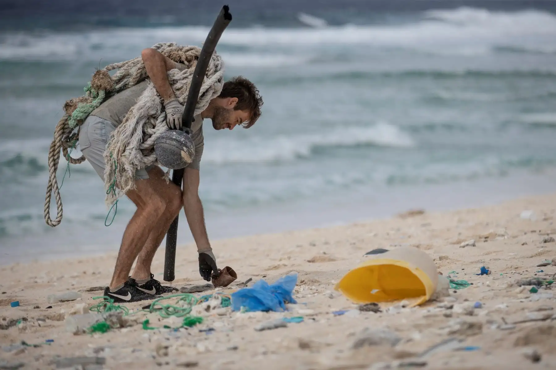 Esta imagen muestra a un miembro del equipo de limpieza de playas recogiendo basura de una playa en la isla Henderson, un miembro deshabitado del archipiélago de las Islas Pitcairn en el sur Océano Pacífico. AFP.