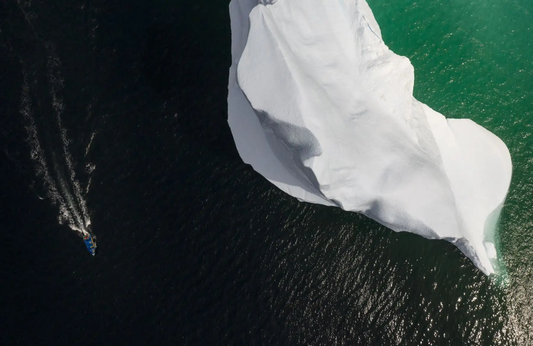 Esta foto aérea muestra el barco del Capitán Edward Kean pasando un Iceberg en la Bahía de Bonavista en Terranova, Canadá. AFP