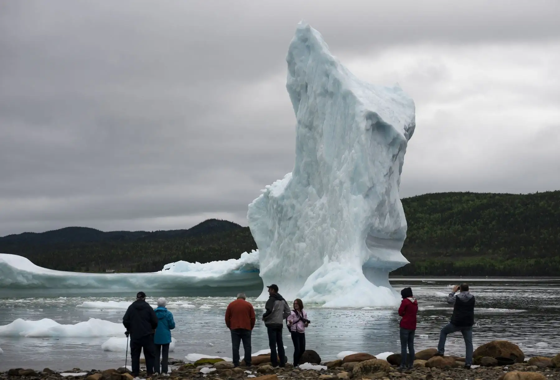 Los turistas miran unos icebergs desde la orilla del mar de King