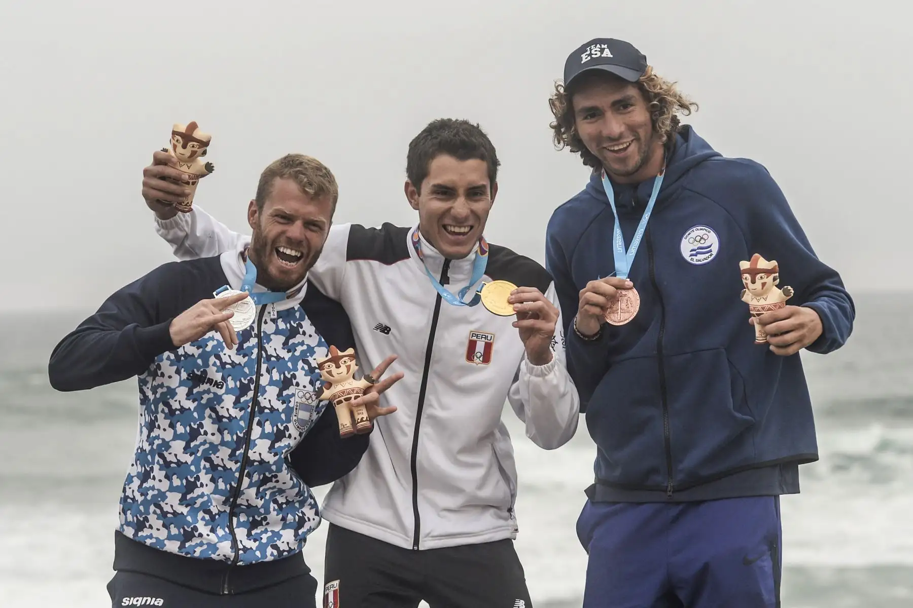 La medalla de oro de Perú Luca Mesinas (C) junto a la medalla de plata argentina Leandro Usuna (L) y Bryan Pérez de El Salvador en el podio para el surf abierto masculino durante los Juegos Panamericanos de Lima 2019.
Foto: AFP