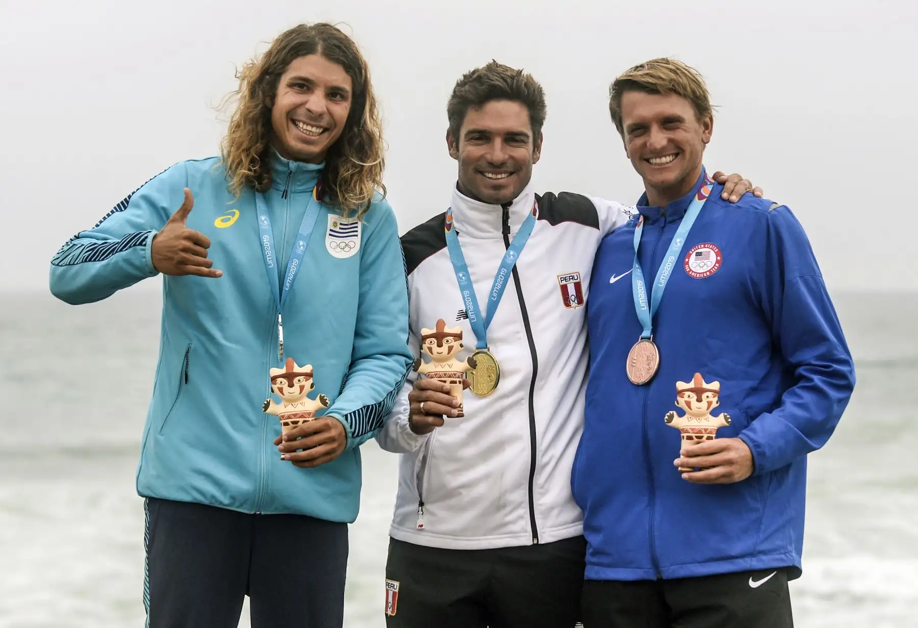 El peruano Benoit Clemente (C) El uruguayo Julian Schweizer (L) y el estadounidense Cole Robbins celebran en el podio del Longboard surfing masculino durante los Juegos Panamericanos de Lima 2019.
Foto: Lima 2019