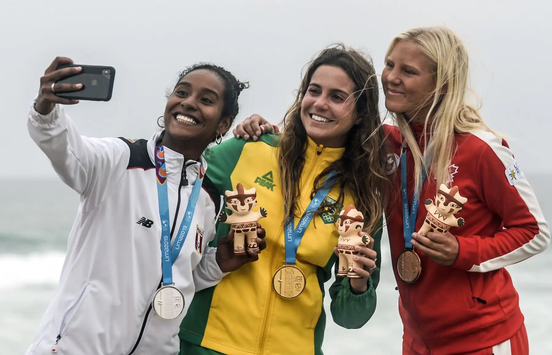 La medalla de oro Chloe Calmon (C) de Brasil junto a las peruanas María Reyes (C) y Mathea Dempfle-Olin (R) en el podio para el surf Longboard femenino durante los Juegos Panamericanos de Lima 2019 .
Foto: AFP