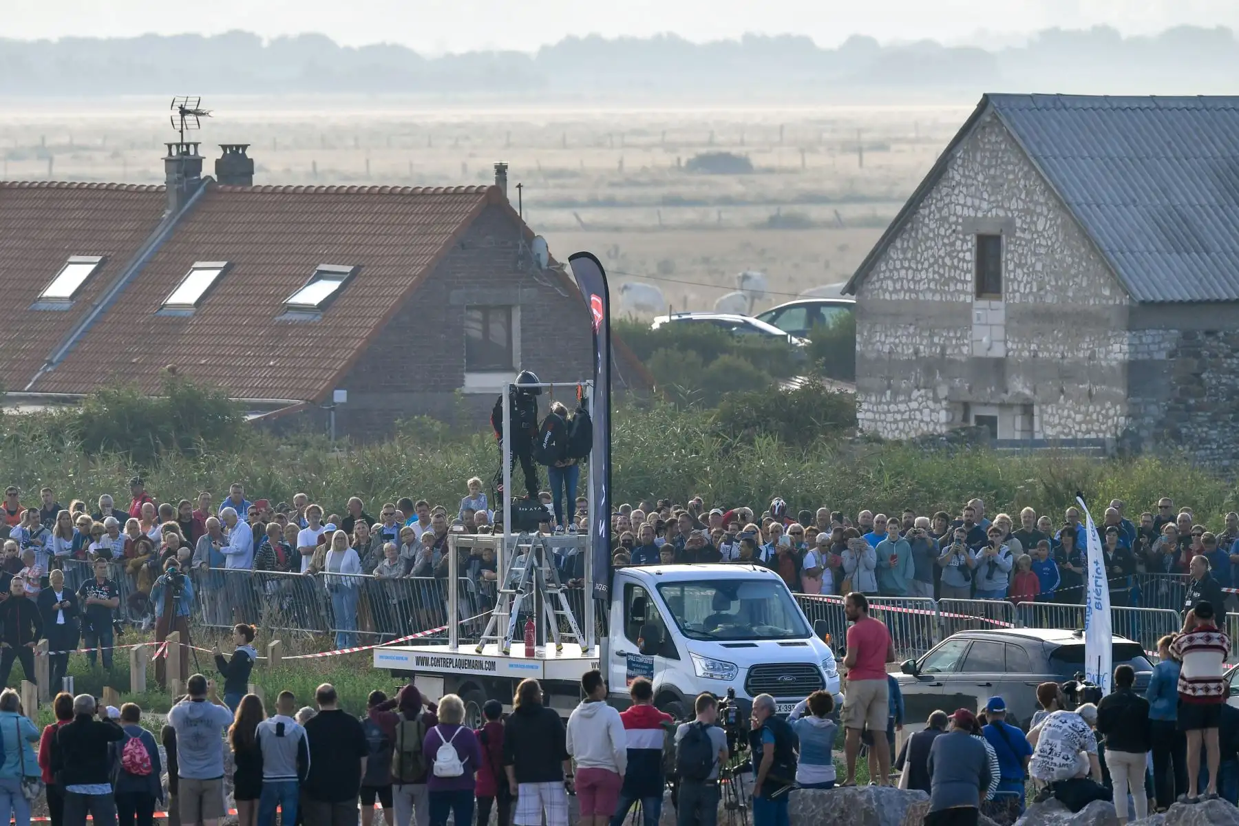 La gente y los medios se reúnen cuando Franky Zapata, flanqueado por su esposa Krystel, se prepara para despegar en su "flyboard" propulsado por un avión desde Sangatte, en el norte de Francia,  en un intento de cruzar los 35 kilómetros de cruce de canales en 20 minutos, manteniendo una velocidad promedio de 140 kilómetros por hora  a una altura de 15-20 metros  sobre el mar.   Foto: AFP