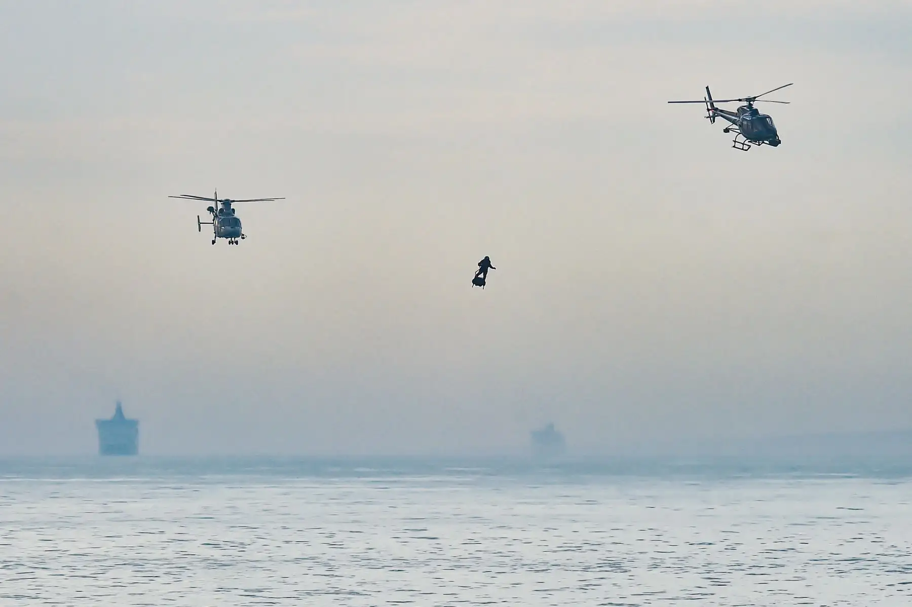 Franky Zapata se para en su "flyboard" propulsado por un jet junto a los helicópteros cuando llega a la bahía de St. Margaret en Dover. AFP