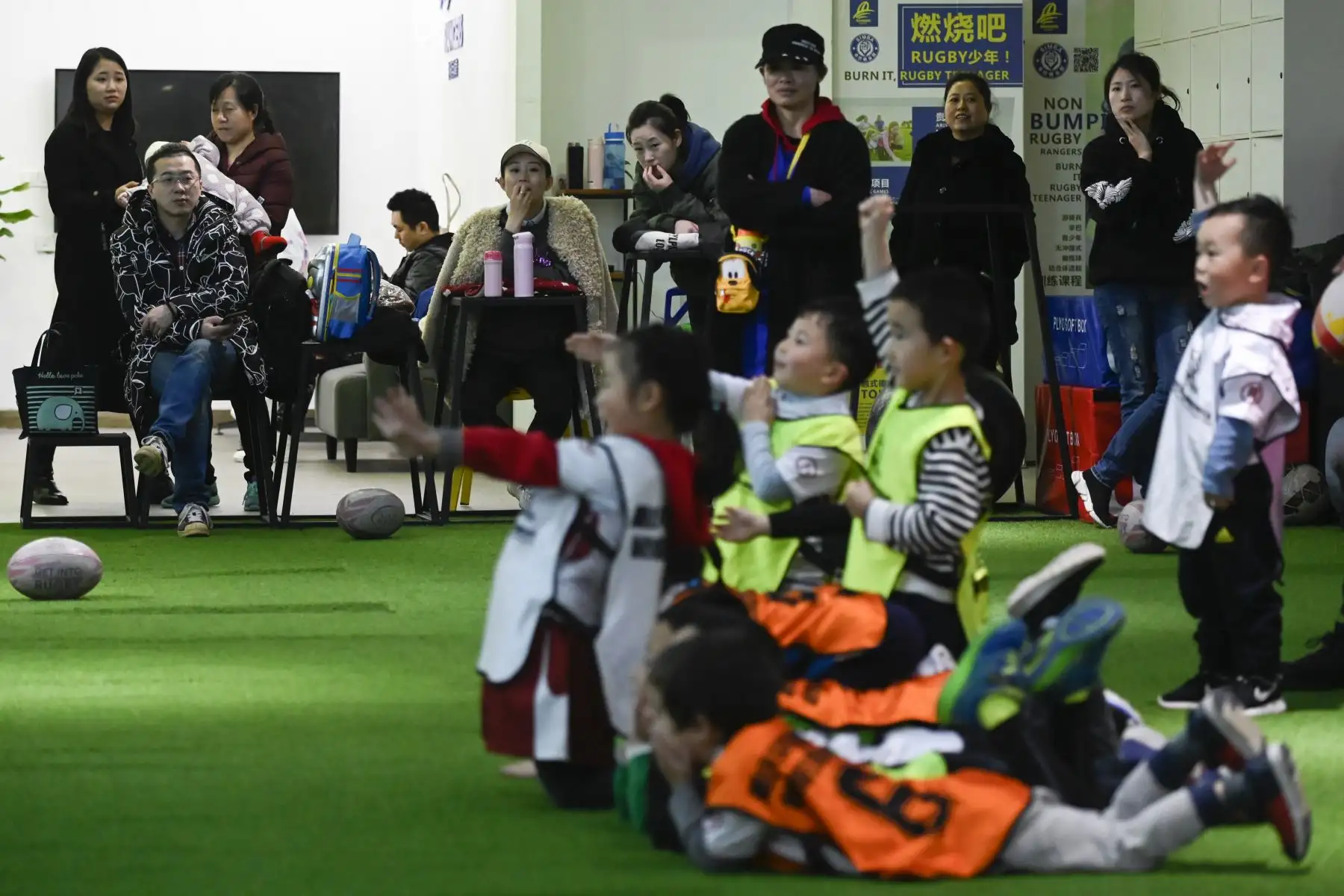 Padres observando a sus hijos participar en una sesión de entrenamiento en un club de rugby juvenil en el municipio de Chongqing, suroeste de China.