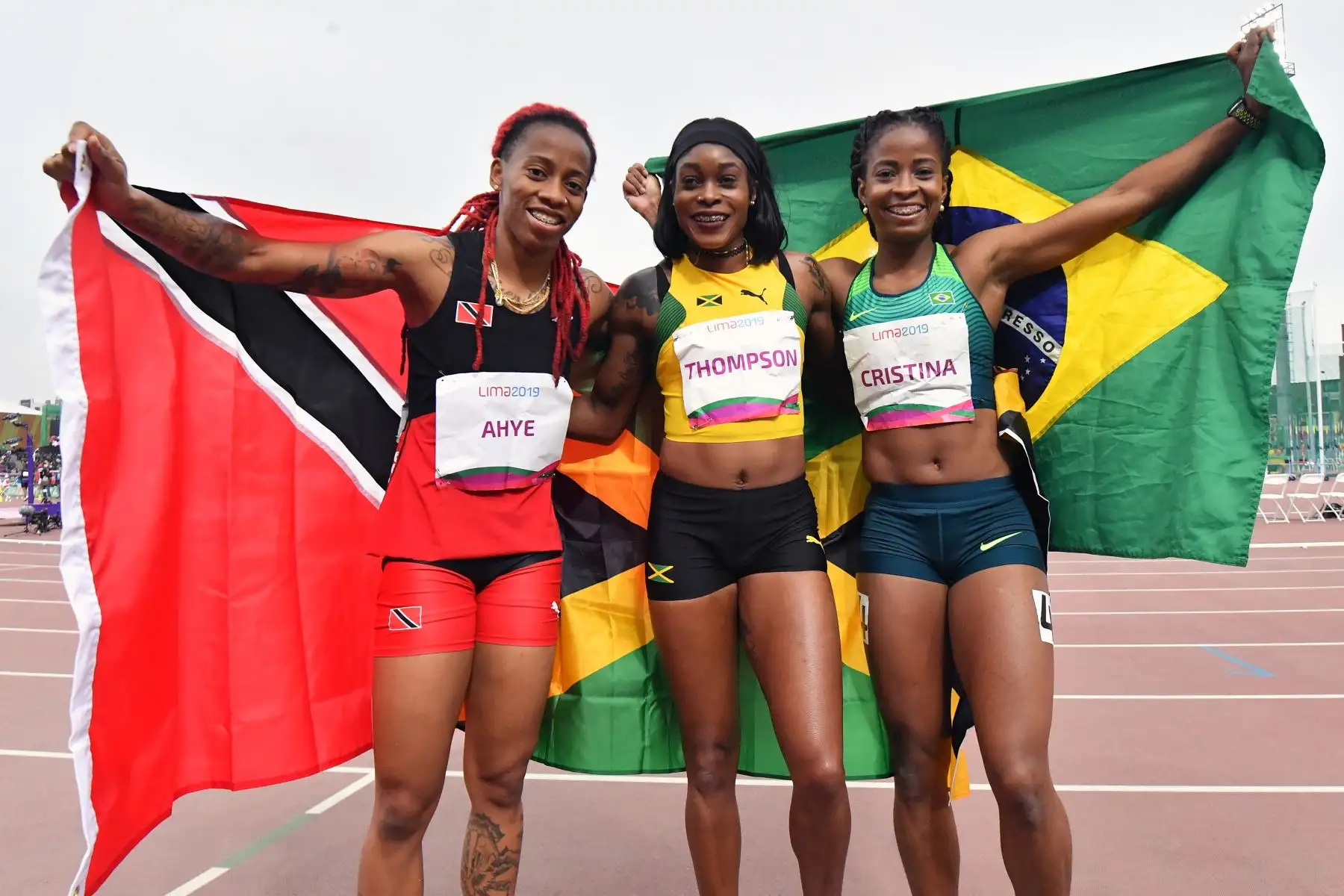 Michelle-Lee Ahye, de Trinidad y Tobago, Elaine Thompson, de Jamaica, y Vitoria Cristina, de Brasil, celebran al final de la final de 100 metros de atletismo femenino durante los Juegos Panamericanos de Lima 2019.
Foto: AFP
