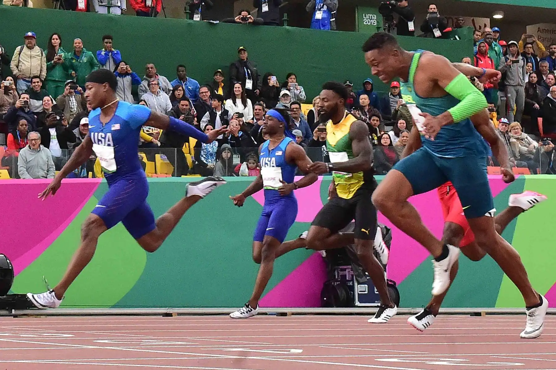 Los atletas cruzan la línea de meta de la final masculina de atletismo de 100 metros durante los Juegos Panamericanos de Lima 2019.
Foto: AFP