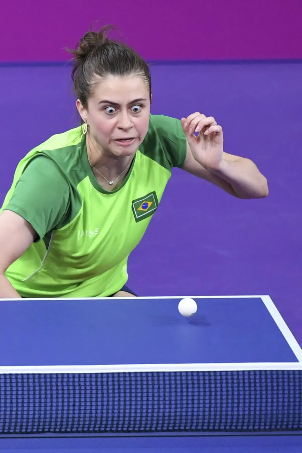 La brasileña Bruna Takahashi mira la pelota mientras juega con Gustavo Tsuboi contra el canadiense Eugene Wang y Mo Zhang durante las finales de dobles de tenis de mesa en los Juegos Panamericanos de Lima 2019. AFP