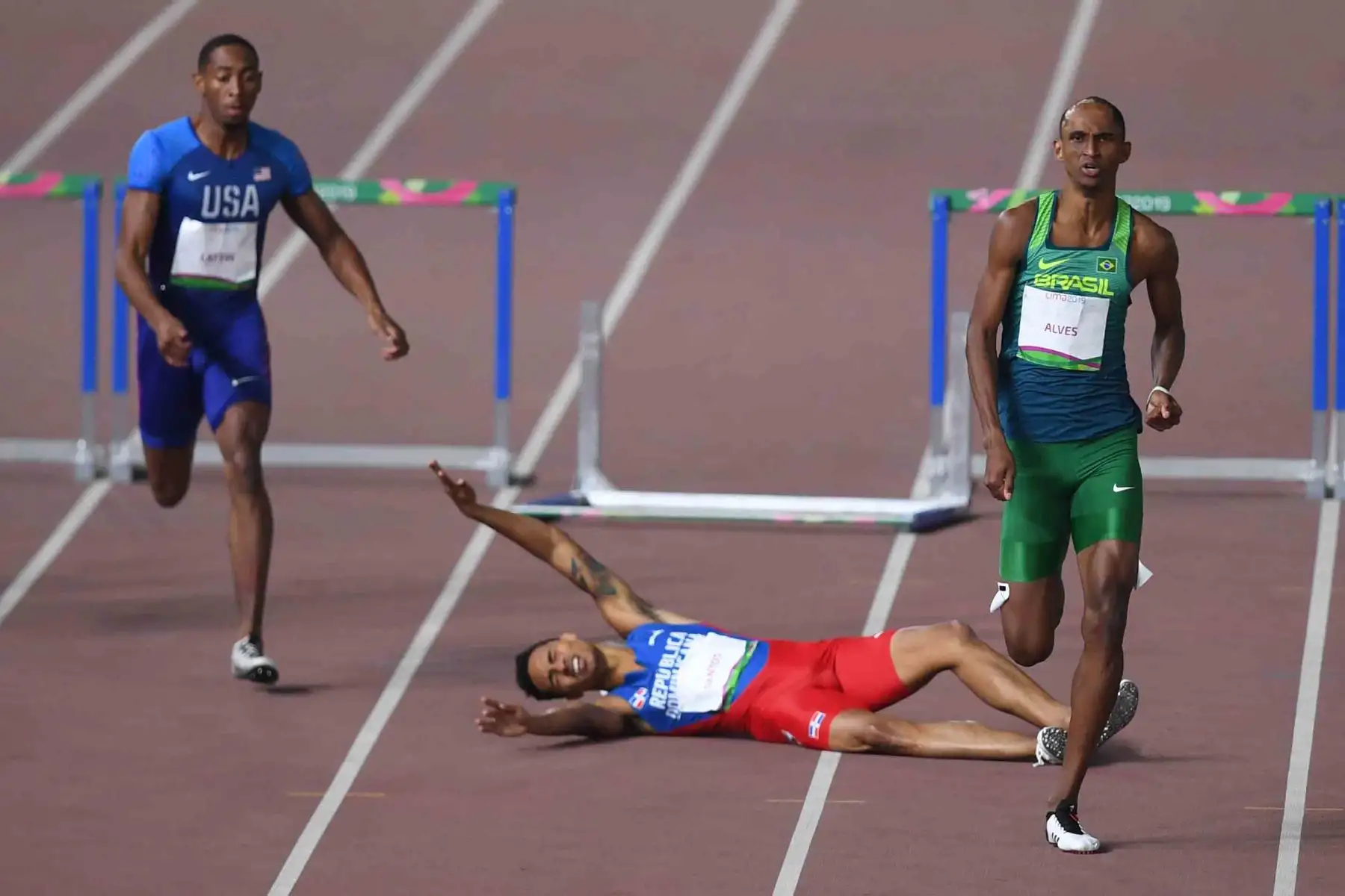 Juander Santos (C) de la República Dominicana se encuentra entre Amere Lattin (L) de los Estados Unidos y Alison Alves de Brasil durante la final de 400 m con vallas de atletismo masculino durante los Juegos Panamericanos de Lima 2019. AFP