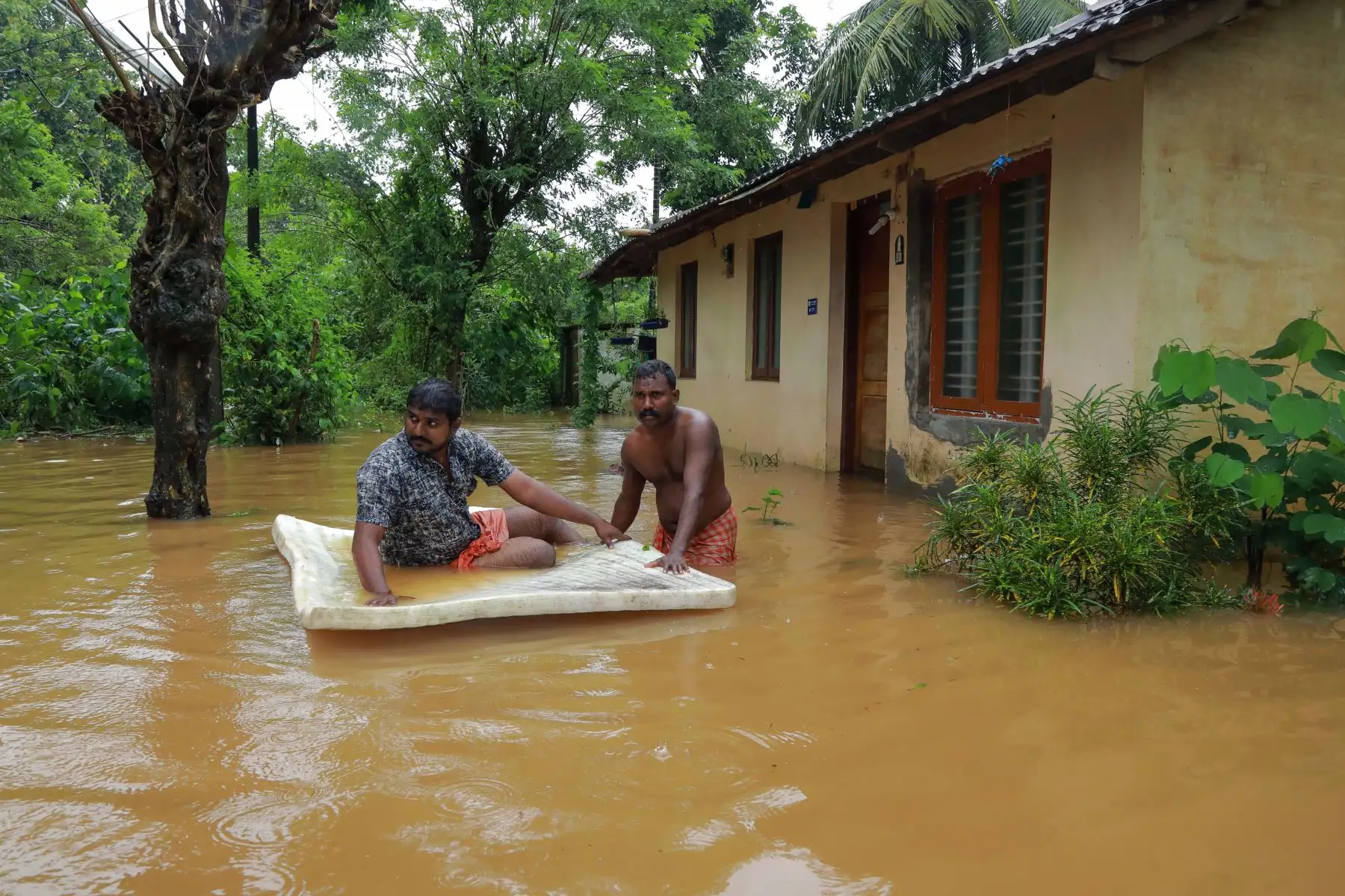 Los hombres pasan por las aguas de la inundación en el área de Eloor en el distrito de Ernakulam, en el estado de Kerala, en el sur de la India. Las inundaciones que han matado a más de 20 personas forzaron el cierre del aeropuerto internacional de Kochi el 9 de agosto como el estado del sur de la India de Kerala se enfrentó a un segundo año consecutivo de lluvias a nivel de crisis. Foto: AFP