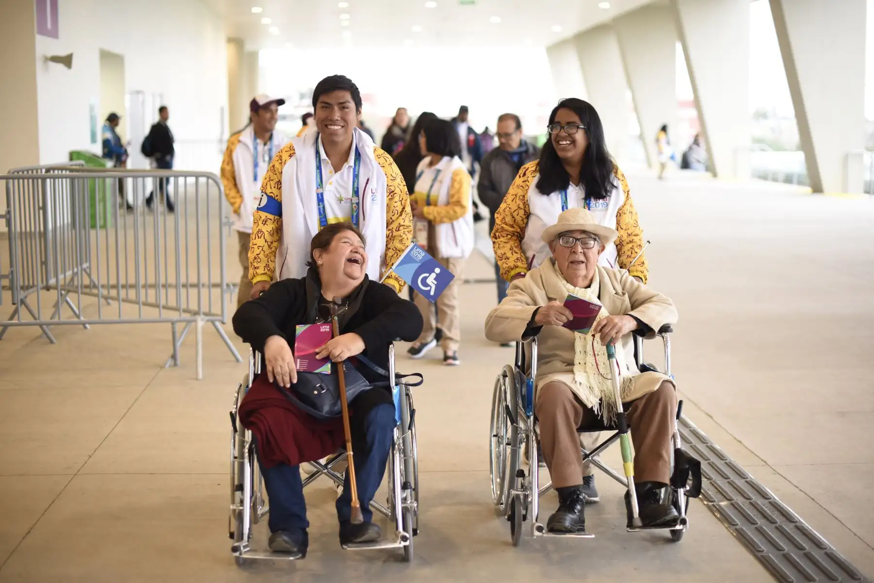 Voluntarios de Lima 2019 llevan a  una pareja de ancianos con silla de ruedas a las tribunas de la  villa atlética de la Videna. Foto: ANDINA/ Lima 2019