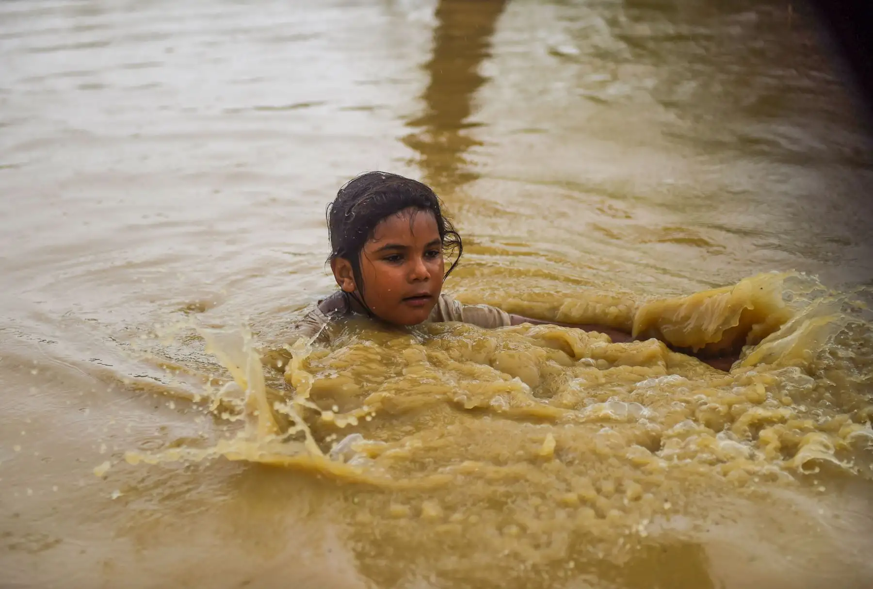 Una niña camina por una calle inundada después de fuertes lluvias monzónicas en las afueras de Karachi. AFP