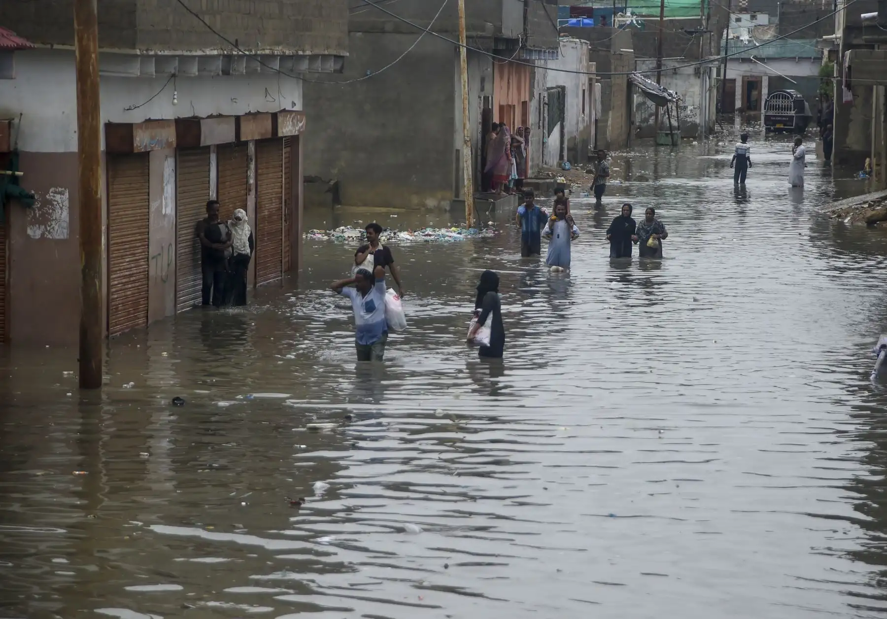 Los residentes caminan por una calle inundada después de fuertes lluvias monzónicas en Karachi. AFP