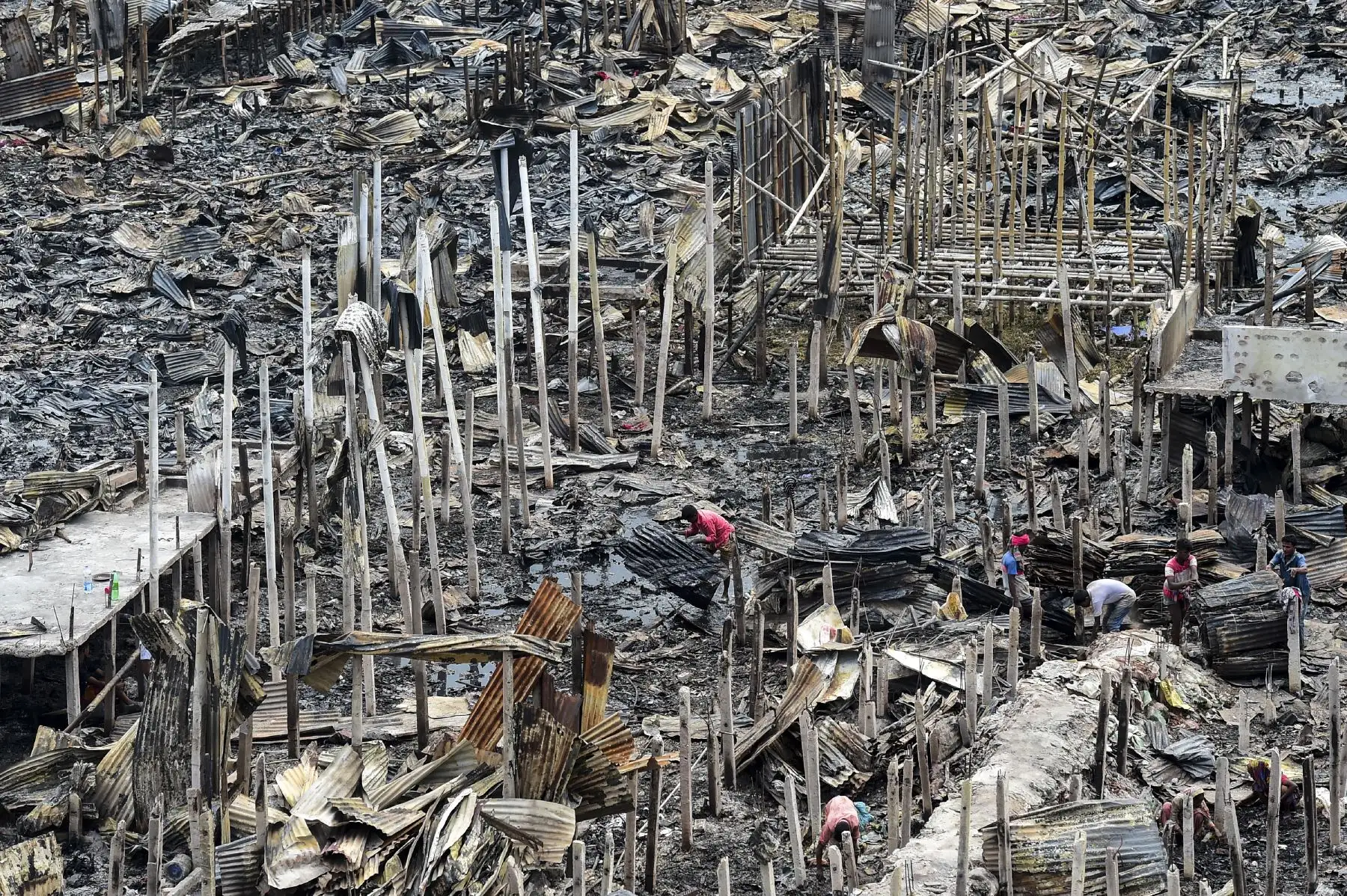 Un residente reúne escombros carbonizados en un barrio pobre en Dhaka, después de que un incendio estalló en el vecindario de Mirpur. 
Foto: AFP