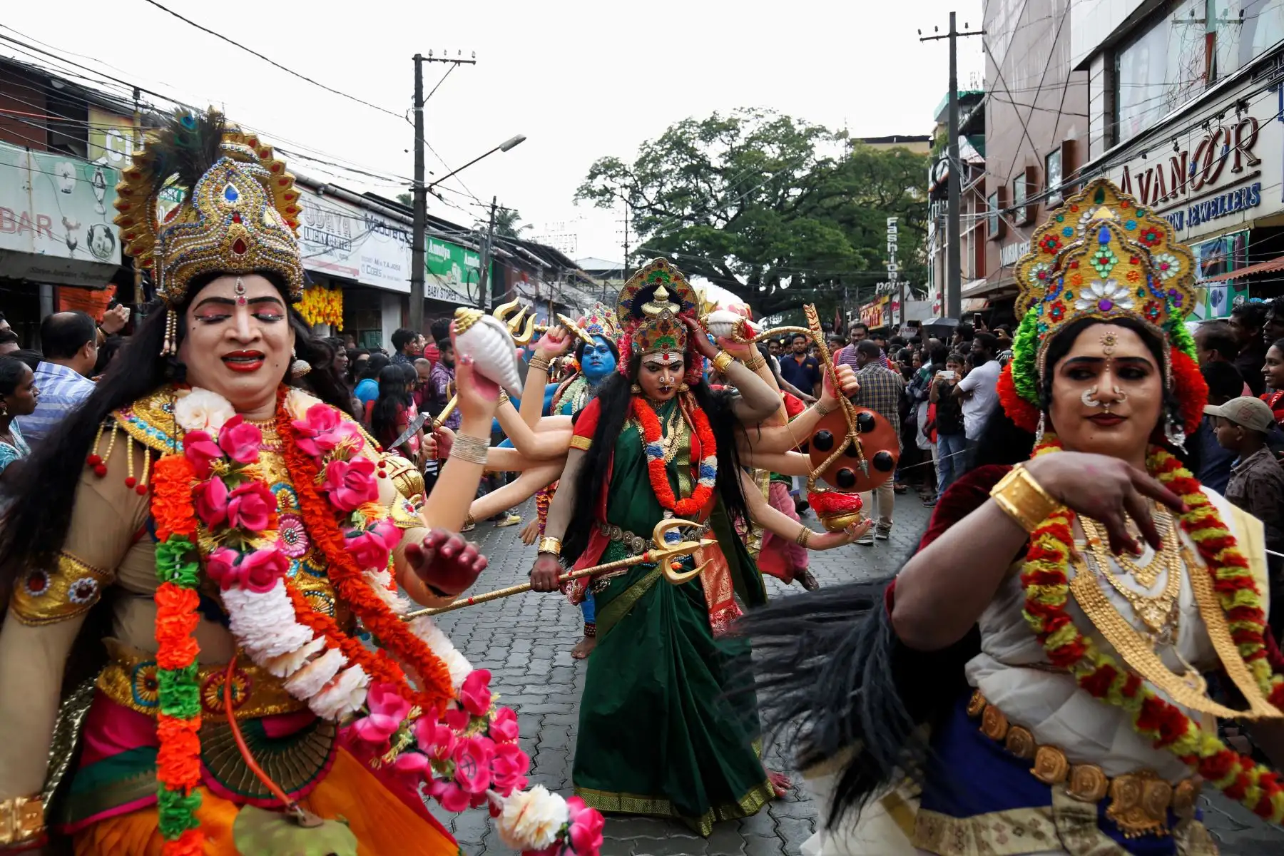 Artistas vestidos como diosas hindúes actúan en una calle mientras participan en la procesión de 